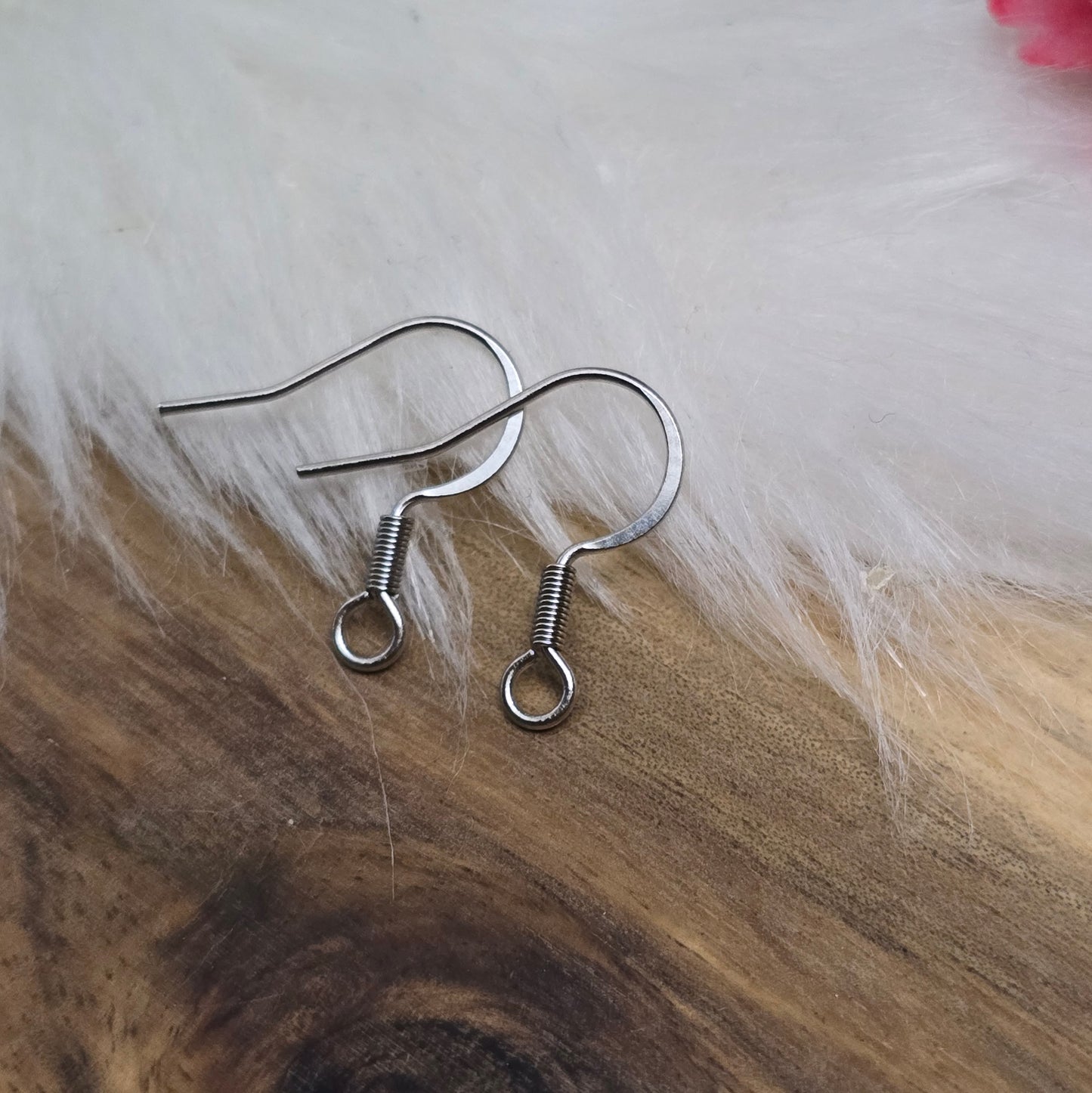 Das Bild zeigt ein Paar French Ohrhaken aus 304 Edelstahl in Silberfarbe. Die Haken haben eine elegante, geschwungene Form mit einer kleinen Öse am unteren Ende, die zur Befestigung von Anhängern oder Perlen dient. Die Oberfläche ist glatt und glänzend, was ihnen ein hochwertiges und modernes Aussehen verleiht. Mit einer Größe von etwa 16 mm sind sie ideal für die Gestaltung individueller Ohrringe.