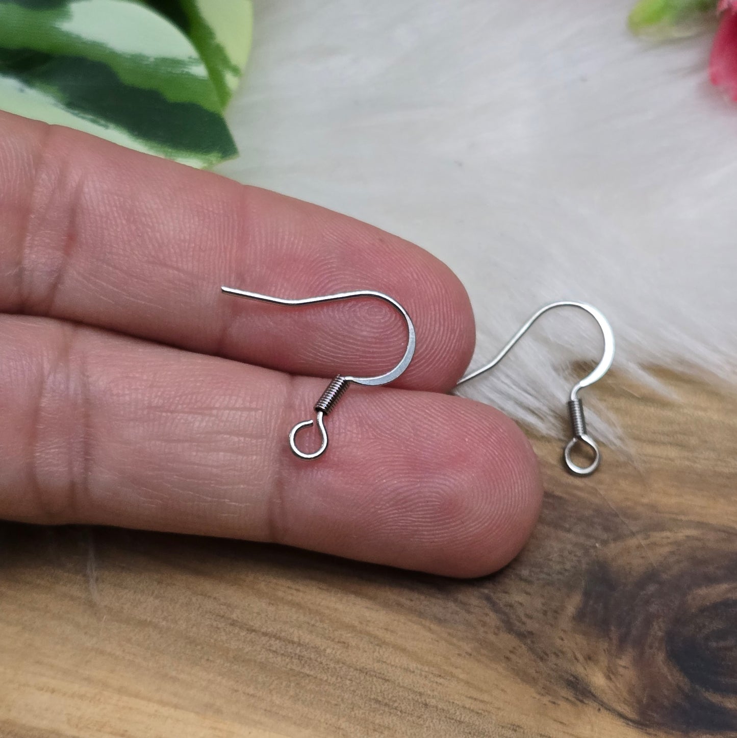 Das Bild zeigt ein Paar French Ohrhaken aus 304 Edelstahl in Silberfarbe. Die Haken haben eine elegante, geschwungene Form mit einer kleinen Öse am unteren Ende, die zur Befestigung von Anhängern oder Perlen dient. Die Oberfläche ist glatt und glänzend, was ihnen ein hochwertiges und modernes Aussehen verleiht. Mit einer Größe von etwa 16 mm sind sie ideal für die Gestaltung individueller Ohrringe.