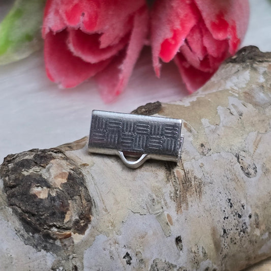 Das Bild zeigt vier Bandklemmen aus Edelstahl mit einer Breite von 13 mm. Jede Klemme ist mit speziellen "Zähnen" am unteren Backenrand ausgestattet, die ein Abrutschen der Bänder verhindern. Die Bandklemmen sind ideal für die Befestigung von Verschlüssen an Stoff- und Lederbändern und eignen sich perfekt für verschiedene Anwendungen wie Kropfbänder, Halsbänder und Armbänder. Die silberfarbene Oberfläche verleiht den Klemmen ein modernes und ansprechendes Aussehen.