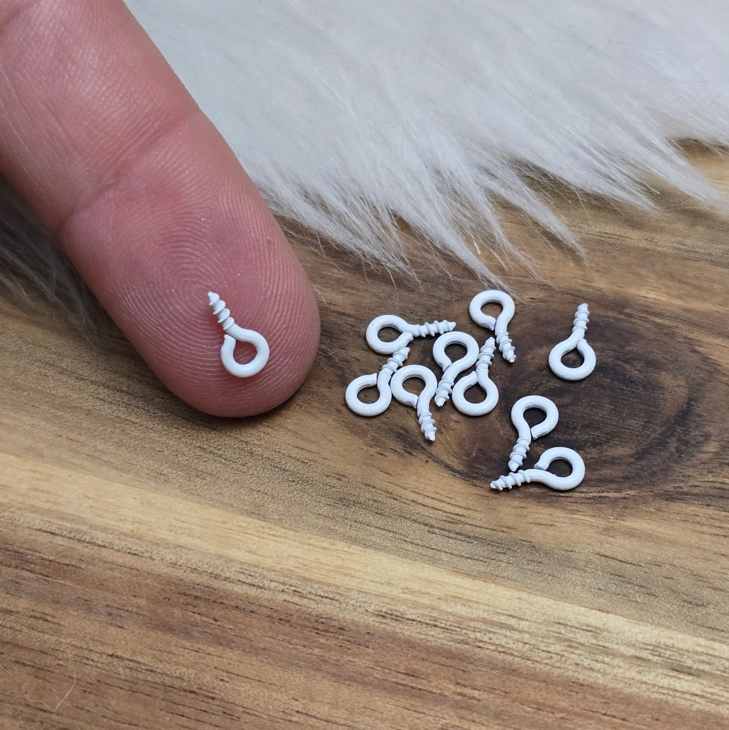 Das Bild zeigt ein Set von 10 farbig lackierten Schraubösen in verschiedenen lebhaften Farben, darunter Hellblau, Grün, Rot, Aqua, Weiß und Rosa. Jede Schrauböse hat die Abmessungen von ca. 8x4mm und ist sorgfältig gestaltet, um eine einfache Anwendung zu ermöglichen. Die Schraubösen sind ideal für das Einschrauben in Materialien wie Holz, Resin oder Acryl, um individuelle Anhänger zu kreieren. Die glänzende Oberfläche der Schraubösen sorgt für einen attraktiven Look, der jedem kreativen Projekt einen farbe