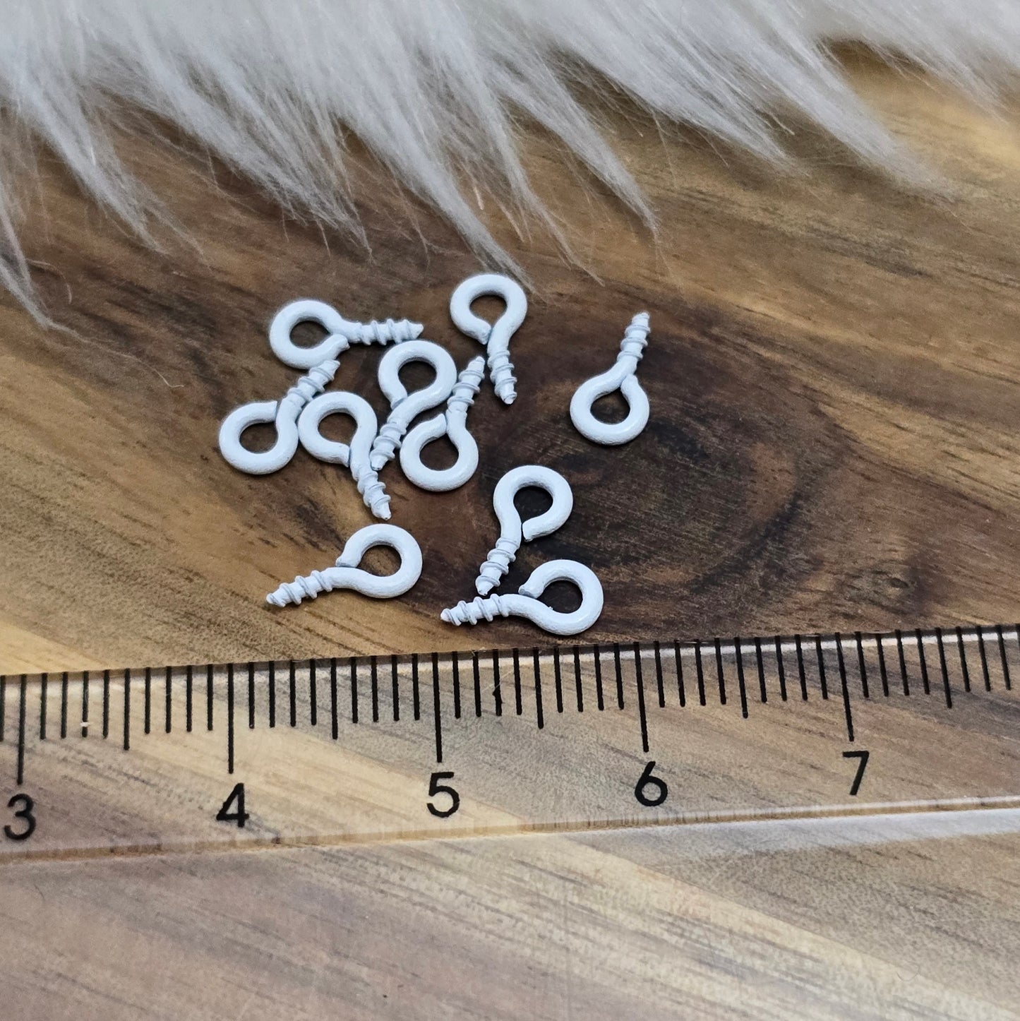 Das Bild zeigt ein Set von 10 farbig lackierten Schraubösen in verschiedenen lebhaften Farben, darunter Hellblau, Grün, Rot, Aqua, Weiß und Rosa. Jede Schrauböse hat die Abmessungen von ca. 8x4mm und ist sorgfältig gestaltet, um eine einfache Anwendung zu ermöglichen. Die Schraubösen sind ideal für das Einschrauben in Materialien wie Holz, Resin oder Acryl, um individuelle Anhänger zu kreieren. Die glänzende Oberfläche der Schraubösen sorgt für einen attraktiven Look, der jedem kreativen Projekt einen farbe