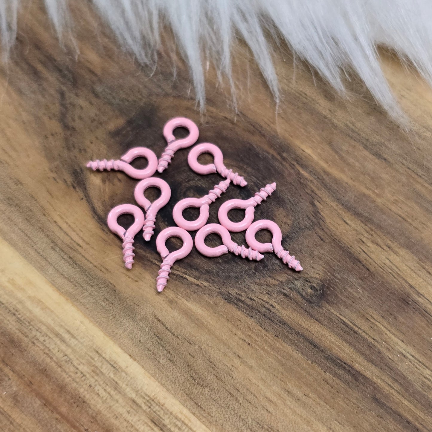 Das Bild zeigt ein Set von 10 farbig lackierten Schraubösen in verschiedenen lebhaften Farben, darunter Hellblau, Grün, Rot, Aqua, Weiß und Rosa. Jede Schrauböse hat die Abmessungen von ca. 8x4mm und ist sorgfältig gestaltet, um eine einfache Anwendung zu ermöglichen. Die Schraubösen sind ideal für das Einschrauben in Materialien wie Holz, Resin oder Acryl, um individuelle Anhänger zu kreieren. Die glänzende Oberfläche der Schraubösen sorgt für einen attraktiven Look, der jedem kreativen Projekt einen farbe