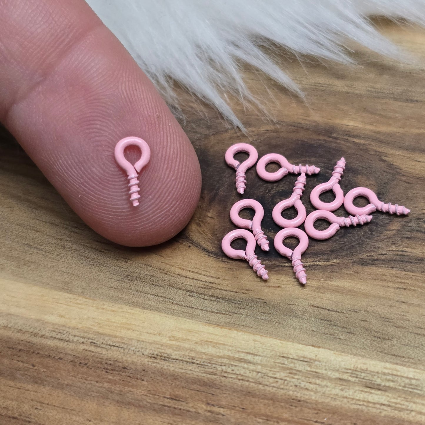 Das Bild zeigt ein Set von 10 farbig lackierten Schraubösen in verschiedenen lebhaften Farben, darunter Hellblau, Grün, Rot, Aqua, Weiß und Rosa. Jede Schrauböse hat die Abmessungen von ca. 8x4mm und ist sorgfältig gestaltet, um eine einfache Anwendung zu ermöglichen. Die Schraubösen sind ideal für das Einschrauben in Materialien wie Holz, Resin oder Acryl, um individuelle Anhänger zu kreieren. Die glänzende Oberfläche der Schraubösen sorgt für einen attraktiven Look, der jedem kreativen Projekt einen farbe