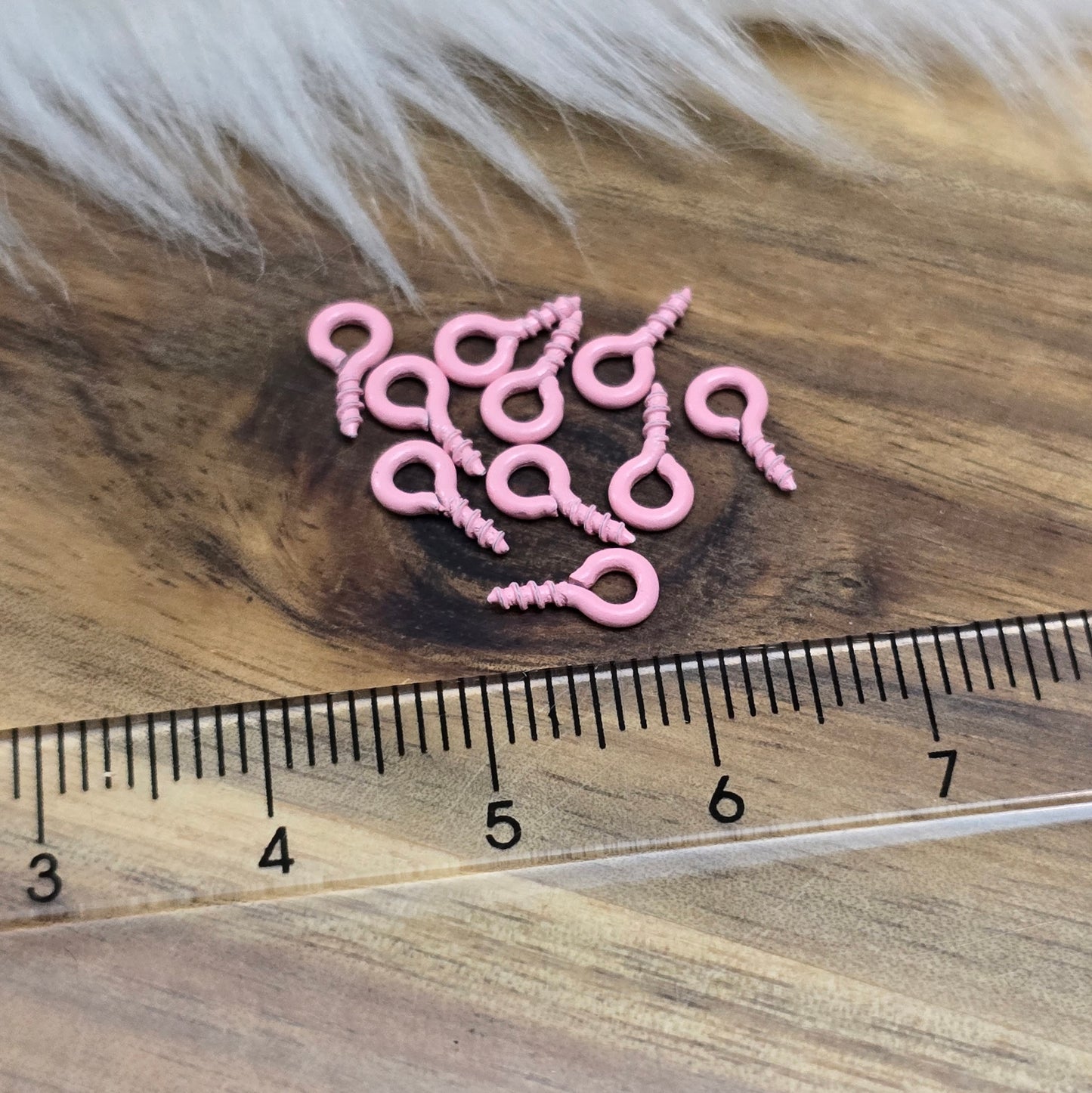 Das Bild zeigt ein Set von 10 farbig lackierten Schraubösen in verschiedenen lebhaften Farben, darunter Hellblau, Grün, Rot, Aqua, Weiß und Rosa. Jede Schrauböse hat die Abmessungen von ca. 8x4mm und ist sorgfältig gestaltet, um eine einfache Anwendung zu ermöglichen. Die Schraubösen sind ideal für das Einschrauben in Materialien wie Holz, Resin oder Acryl, um individuelle Anhänger zu kreieren. Die glänzende Oberfläche der Schraubösen sorgt für einen attraktiven Look, der jedem kreativen Projekt einen farbe
