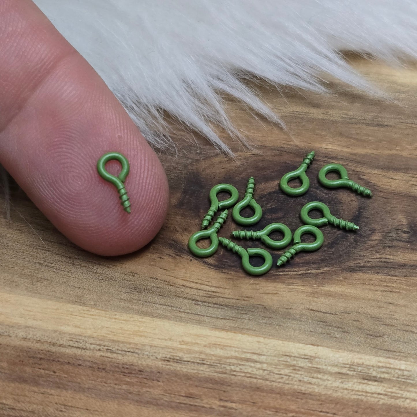 Das Bild zeigt ein Set von 10 farbig lackierten Schraubösen in verschiedenen lebhaften Farben, darunter Hellblau, Grün, Rot, Aqua, Weiß und Rosa. Jede Schrauböse hat die Abmessungen von ca. 8x4mm und ist sorgfältig gestaltet, um eine einfache Anwendung zu ermöglichen. Die Schraubösen sind ideal für das Einschrauben in Materialien wie Holz, Resin oder Acryl, um individuelle Anhänger zu kreieren. Die glänzende Oberfläche der Schraubösen sorgt für einen attraktiven Look, der jedem kreativen Projekt einen farbe