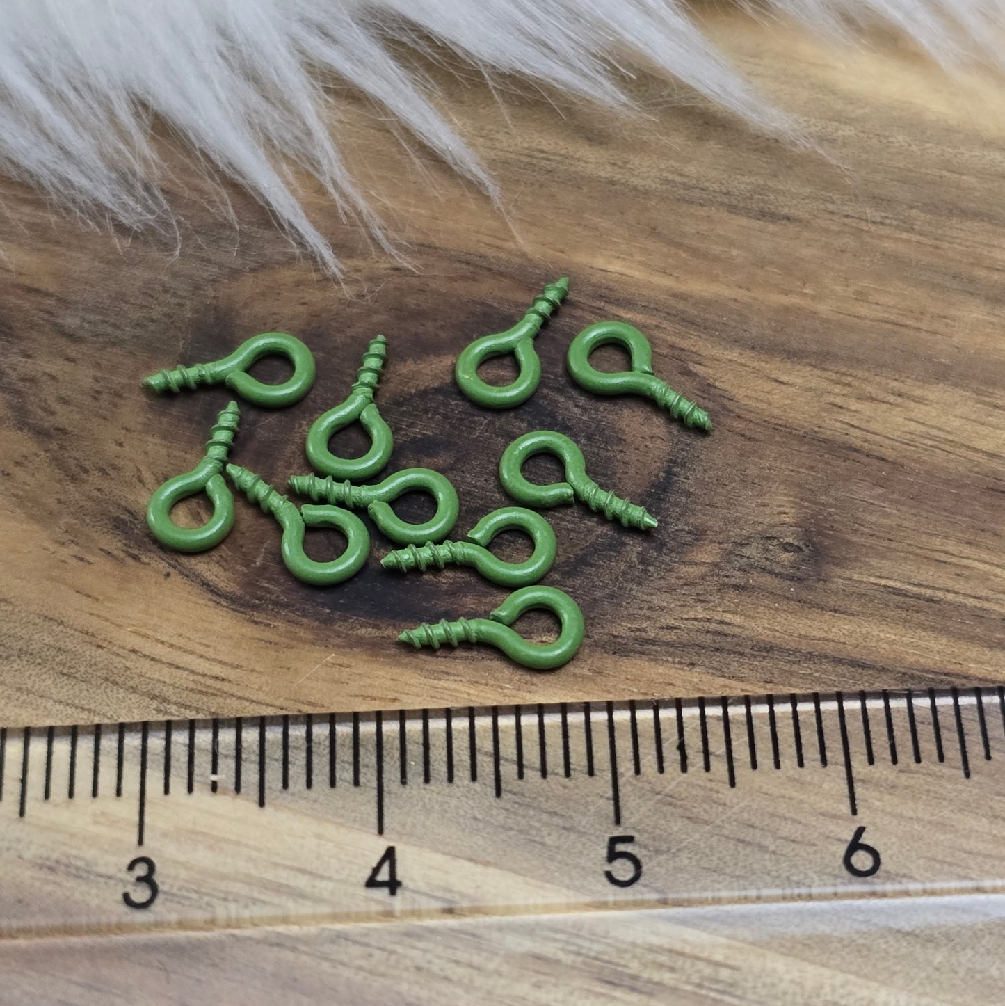 Das Bild zeigt ein Set von 10 farbig lackierten Schraubösen in verschiedenen lebhaften Farben, darunter Hellblau, Grün, Rot, Aqua, Weiß und Rosa. Jede Schrauböse hat die Abmessungen von ca. 8x4mm und ist sorgfältig gestaltet, um eine einfache Anwendung zu ermöglichen. Die Schraubösen sind ideal für das Einschrauben in Materialien wie Holz, Resin oder Acryl, um individuelle Anhänger zu kreieren. Die glänzende Oberfläche der Schraubösen sorgt für einen attraktiven Look, der jedem kreativen Projekt einen farbe