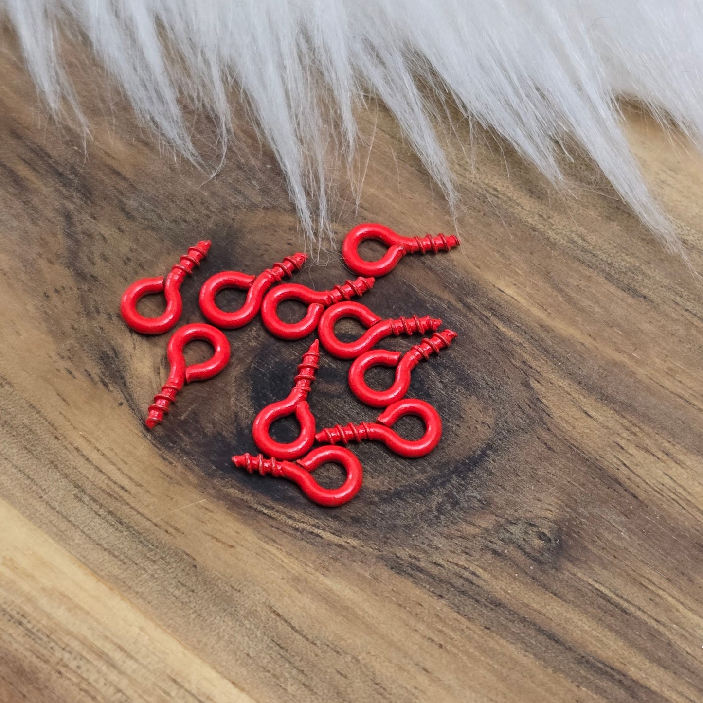 Das Bild zeigt ein Set von 10 farbig lackierten Schraubösen in verschiedenen lebhaften Farben, darunter Hellblau, Grün, Rot, Aqua, Weiß und Rosa. Jede Schrauböse hat die Abmessungen von ca. 8x4mm und ist sorgfältig gestaltet, um eine einfache Anwendung zu ermöglichen. Die Schraubösen sind ideal für das Einschrauben in Materialien wie Holz, Resin oder Acryl, um individuelle Anhänger zu kreieren. Die glänzende Oberfläche der Schraubösen sorgt für einen attraktiven Look, der jedem kreativen Projekt einen farbe