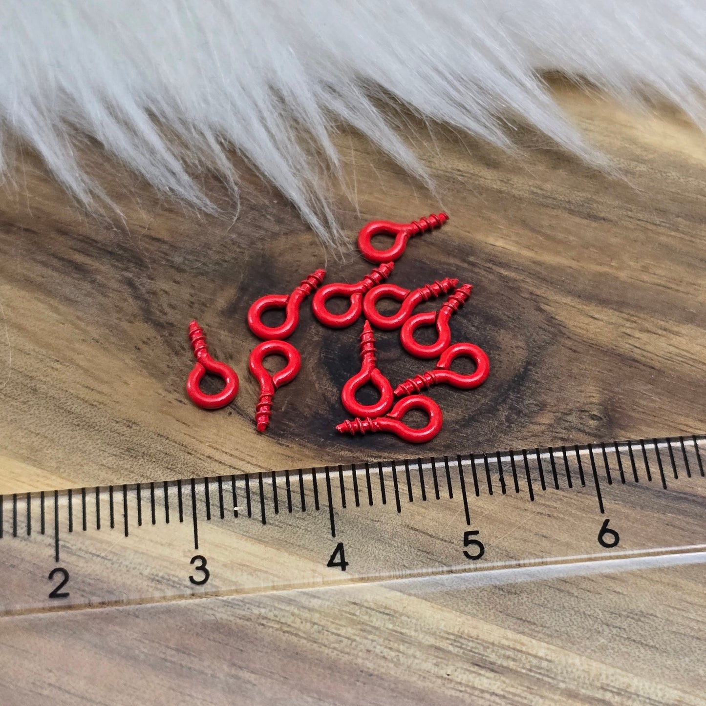 Das Bild zeigt ein Set von 10 farbig lackierten Schraubösen in verschiedenen lebhaften Farben, darunter Hellblau, Grün, Rot, Aqua, Weiß und Rosa. Jede Schrauböse hat die Abmessungen von ca. 8x4mm und ist sorgfältig gestaltet, um eine einfache Anwendung zu ermöglichen. Die Schraubösen sind ideal für das Einschrauben in Materialien wie Holz, Resin oder Acryl, um individuelle Anhänger zu kreieren. Die glänzende Oberfläche der Schraubösen sorgt für einen attraktiven Look, der jedem kreativen Projekt einen farbe