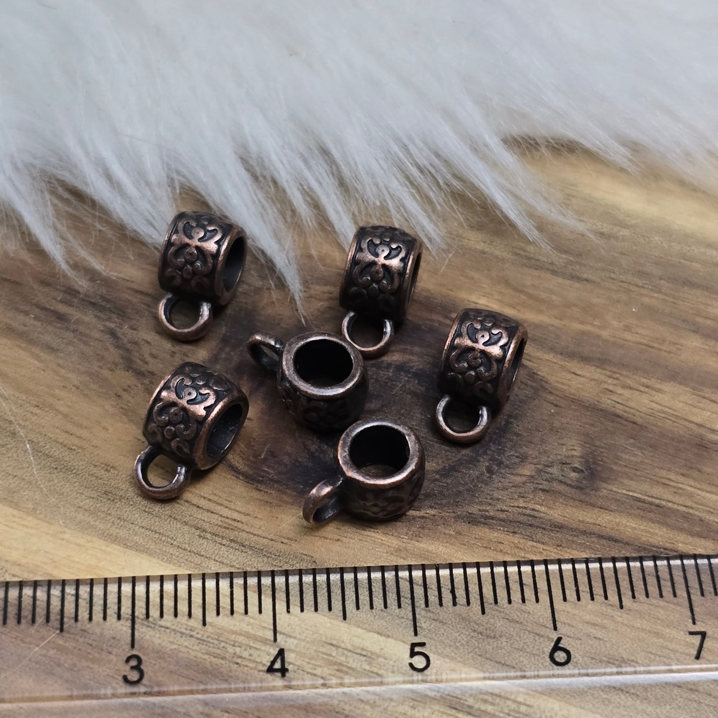 Das Bild zeigt antik kupferfarbige Metallperlen mit Öse.