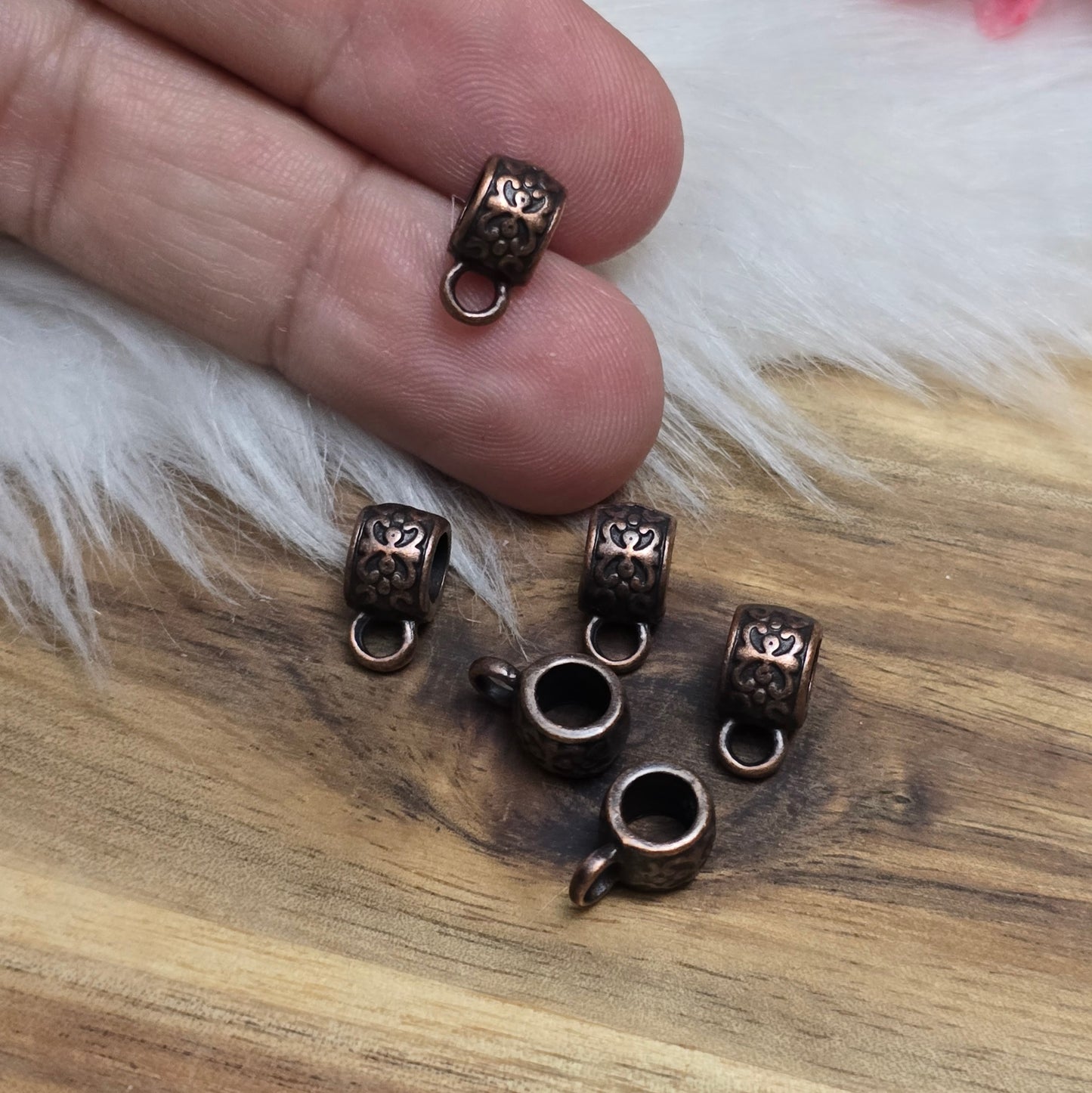 Das Bild zeigt antik kupferfarbige Metallperlen mit Öse.
