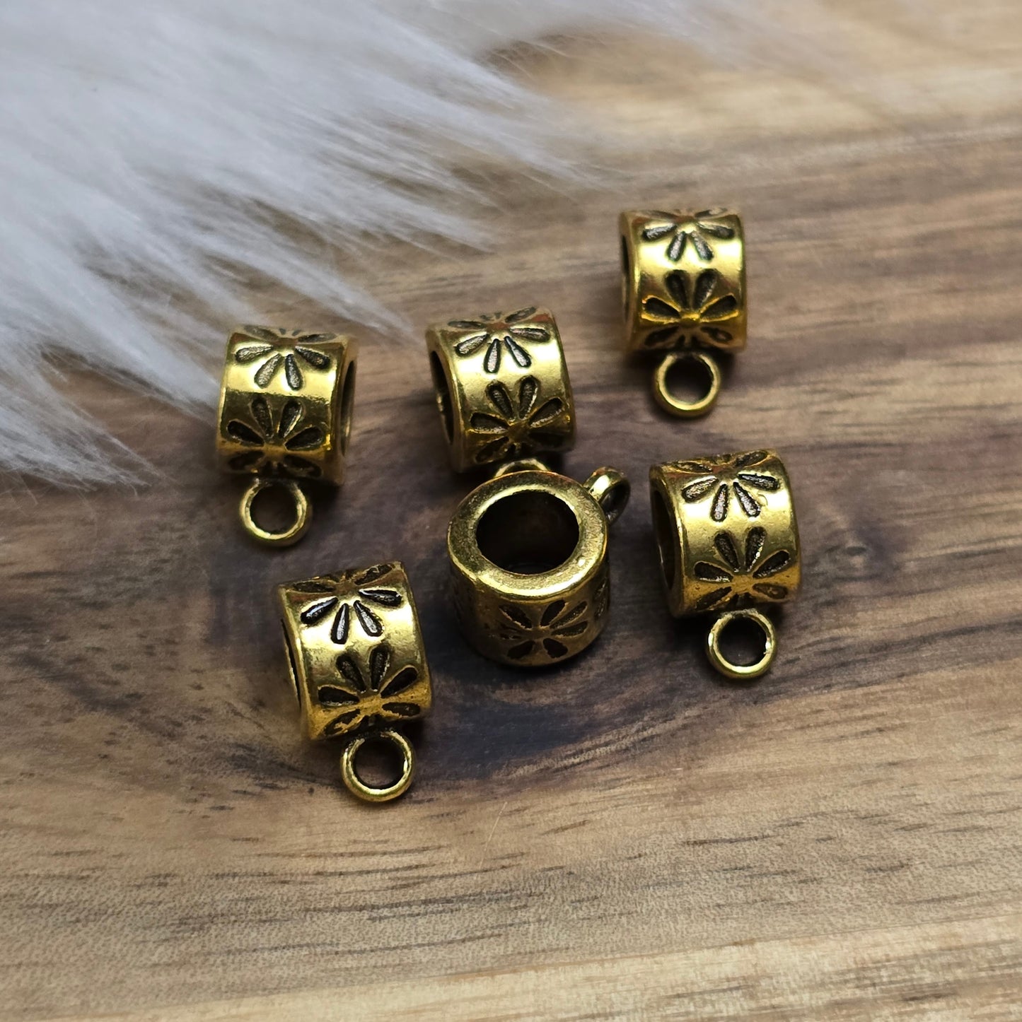 Das Bild zeigt 12 antik goldfarbene Metallperlen mit integrierter Anhängeröse. Die runden Perlen haben eine glatte Oberfläche und eine Öffnung zum einfachen Auffädeln auf Ketten oder Armbänder. Die fest angebrachte Öse ermöglicht das Befestigen von Anhängern für individuelle Schmuckdesigns.