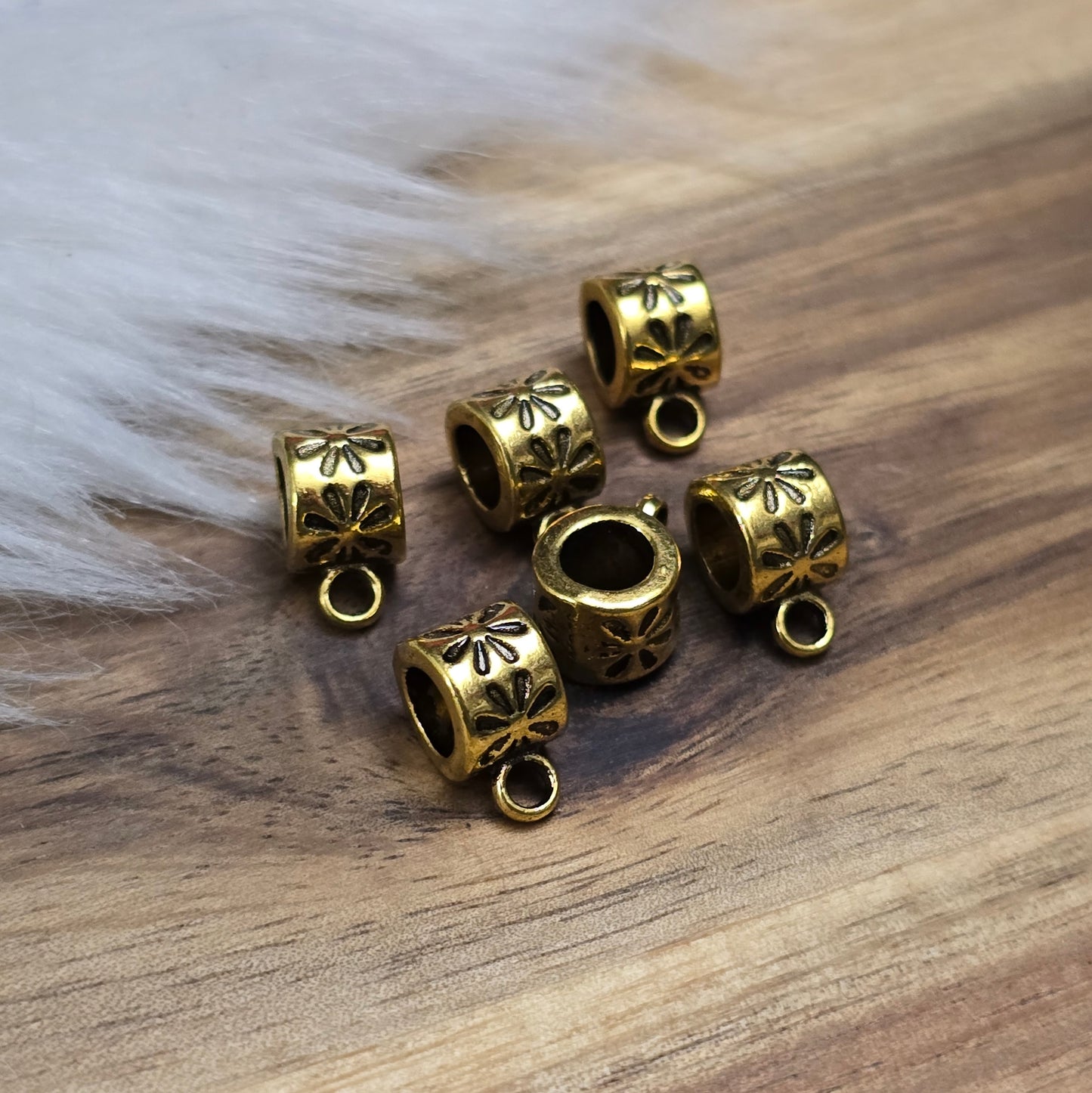 Das Bild zeigt 12 antik goldfarbene Metallperlen mit integrierter Anhängeröse. Die runden Perlen haben eine glatte Oberfläche und eine Öffnung zum einfachen Auffädeln auf Ketten oder Armbänder. Die fest angebrachte Öse ermöglicht das Befestigen von Anhängern für individuelle Schmuckdesigns.