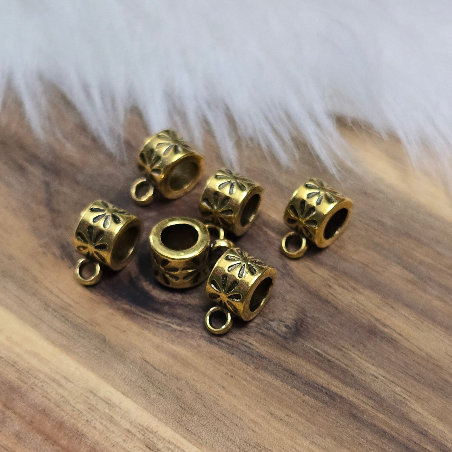 Das Bild zeigt 12 antik goldfarbene Metallperlen mit integrierter Anhängeröse. Die runden Perlen haben eine glatte Oberfläche und eine Öffnung zum einfachen Auffädeln auf Ketten oder Armbänder. Die fest angebrachte Öse ermöglicht das Befestigen von Anhängern für individuelle Schmuckdesigns.