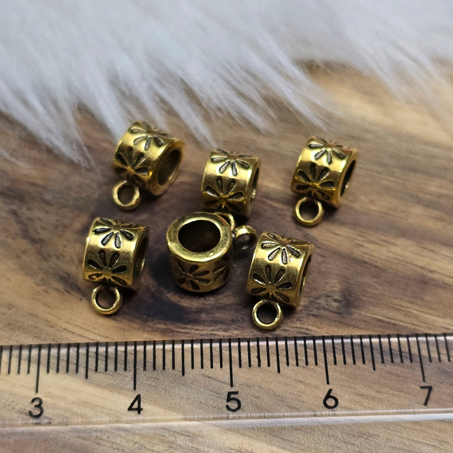 Das Bild zeigt 12 antik goldfarbene Metallperlen mit integrierter Anhängeröse. Die runden Perlen haben eine glatte Oberfläche und eine Öffnung zum einfachen Auffädeln auf Ketten oder Armbänder. Die fest angebrachte Öse ermöglicht das Befestigen von Anhängern für individuelle Schmuckdesigns.