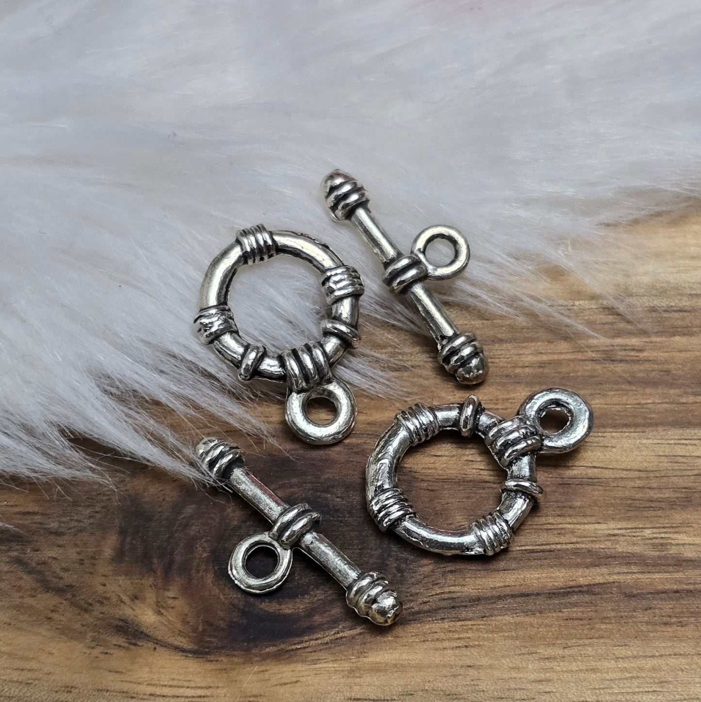 Die Abbildung zeigt zwei antik silberfarbene Knebelverschlüsse, bestehend aus einem Ring und einem Stab. Diese hochwertigen Verschlüsse bieten eine elegante Lösung für Schmuckstücke wie Armbänder und Ketten. Ihr klassisches Design verleiht jedem Projekt eine dekorative Note und sorgt gleichzeitig für eine sichere Verschlussmöglichkeit.