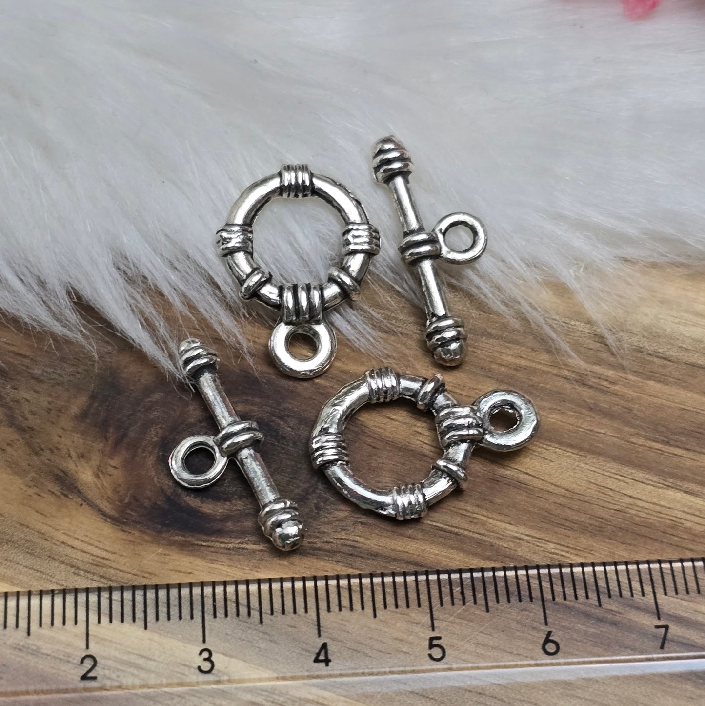 Die Abbildung zeigt zwei antik silberfarbene Knebelverschlüsse, bestehend aus einem Ring und einem Stab. Diese hochwertigen Verschlüsse bieten eine elegante Lösung für Schmuckstücke wie Armbänder und Ketten. Ihr klassisches Design verleiht jedem Projekt eine dekorative Note und sorgt gleichzeitig für eine sichere Verschlussmöglichkeit.