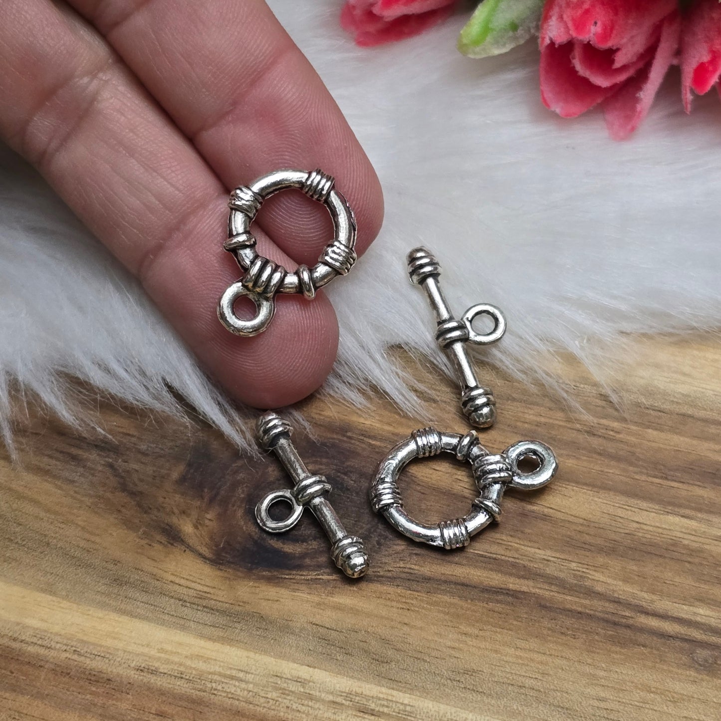 Die Abbildung zeigt zwei antik silberfarbene Knebelverschlüsse, bestehend aus einem Ring und einem Stab. Diese hochwertigen Verschlüsse bieten eine elegante Lösung für Schmuckstücke wie Armbänder und Ketten. Ihr klassisches Design verleiht jedem Projekt eine dekorative Note und sorgt gleichzeitig für eine sichere Verschlussmöglichkeit.