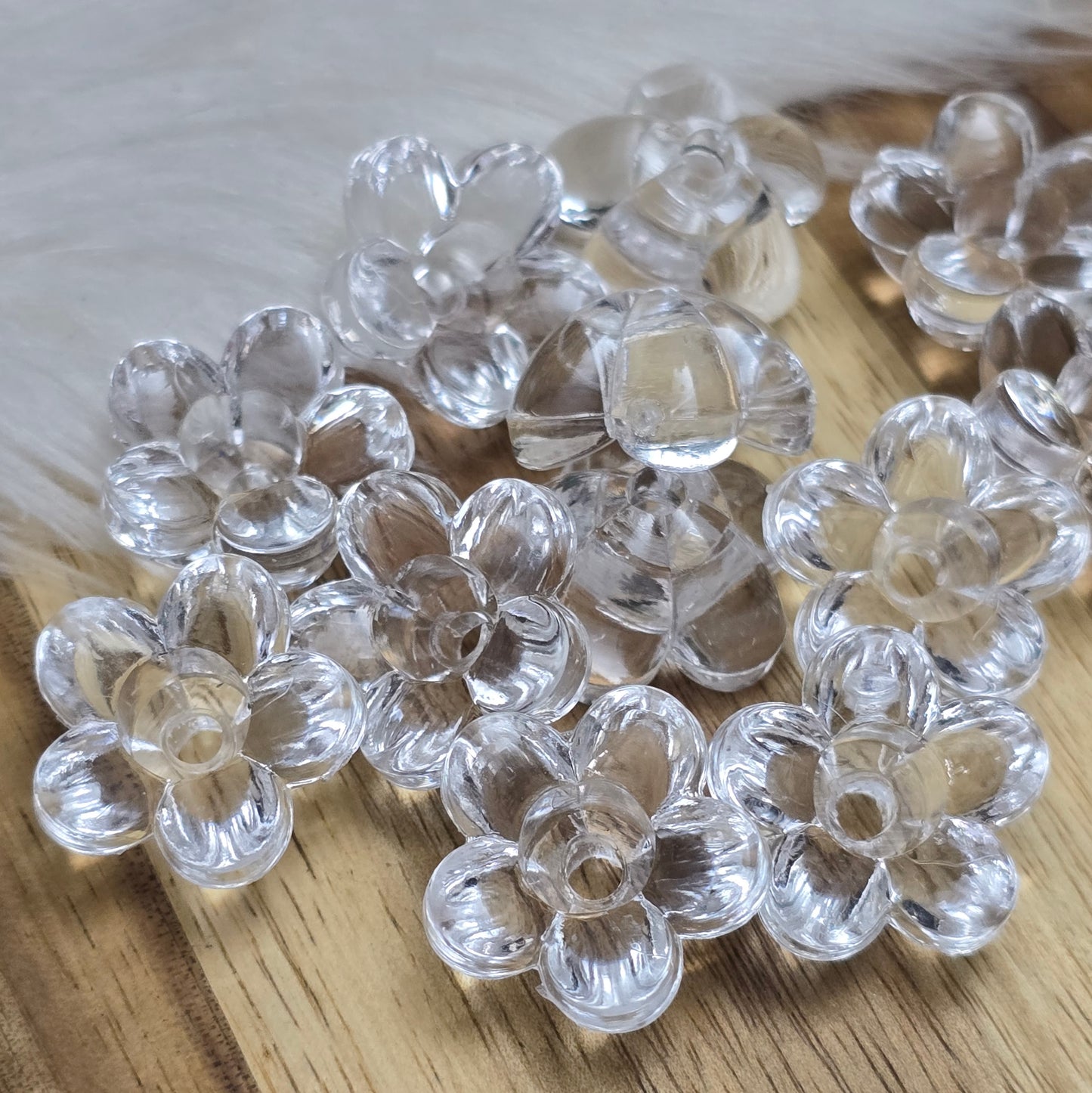 Klar transparente Acryl-Blumenperlen (18 mm) mit glänzender Oberfläche. Die filigrane Blütenform verleiht Schmuckstücken und Dekorationen eine elegante Note. Mit einem 3,5 mm großen Fädelloch lassen sie sich leicht auf Bänder oder Schnüre auffädeln. Ideal für DIY-Projekte, Hochzeiten oder Bastelarbeiten.