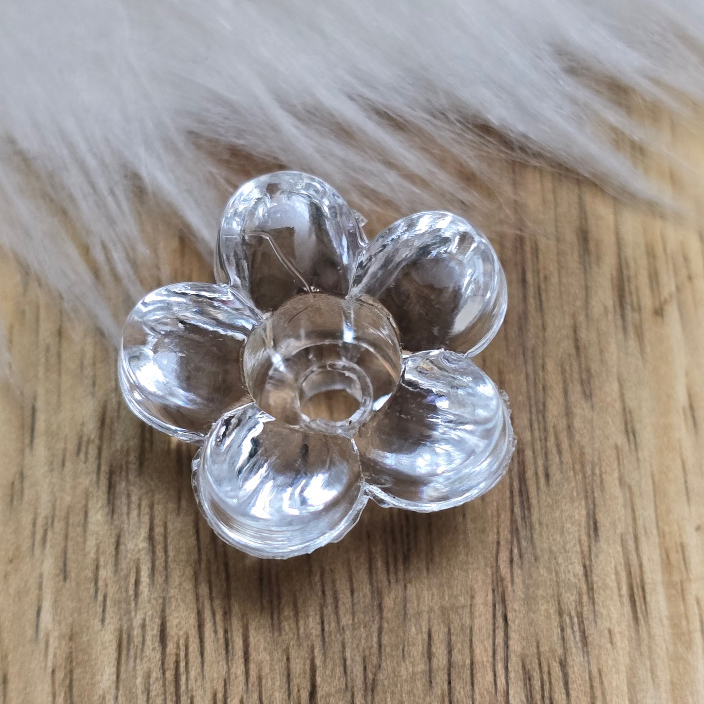 Klar transparente Acryl-Blumenperlen (18 mm) mit glänzender Oberfläche. Die filigrane Blütenform verleiht Schmuckstücken und Dekorationen eine elegante Note. Mit einem 3,5 mm großen Fädelloch lassen sie sich leicht auf Bänder oder Schnüre auffädeln. Ideal für DIY-Projekte, Hochzeiten oder Bastelarbeiten.