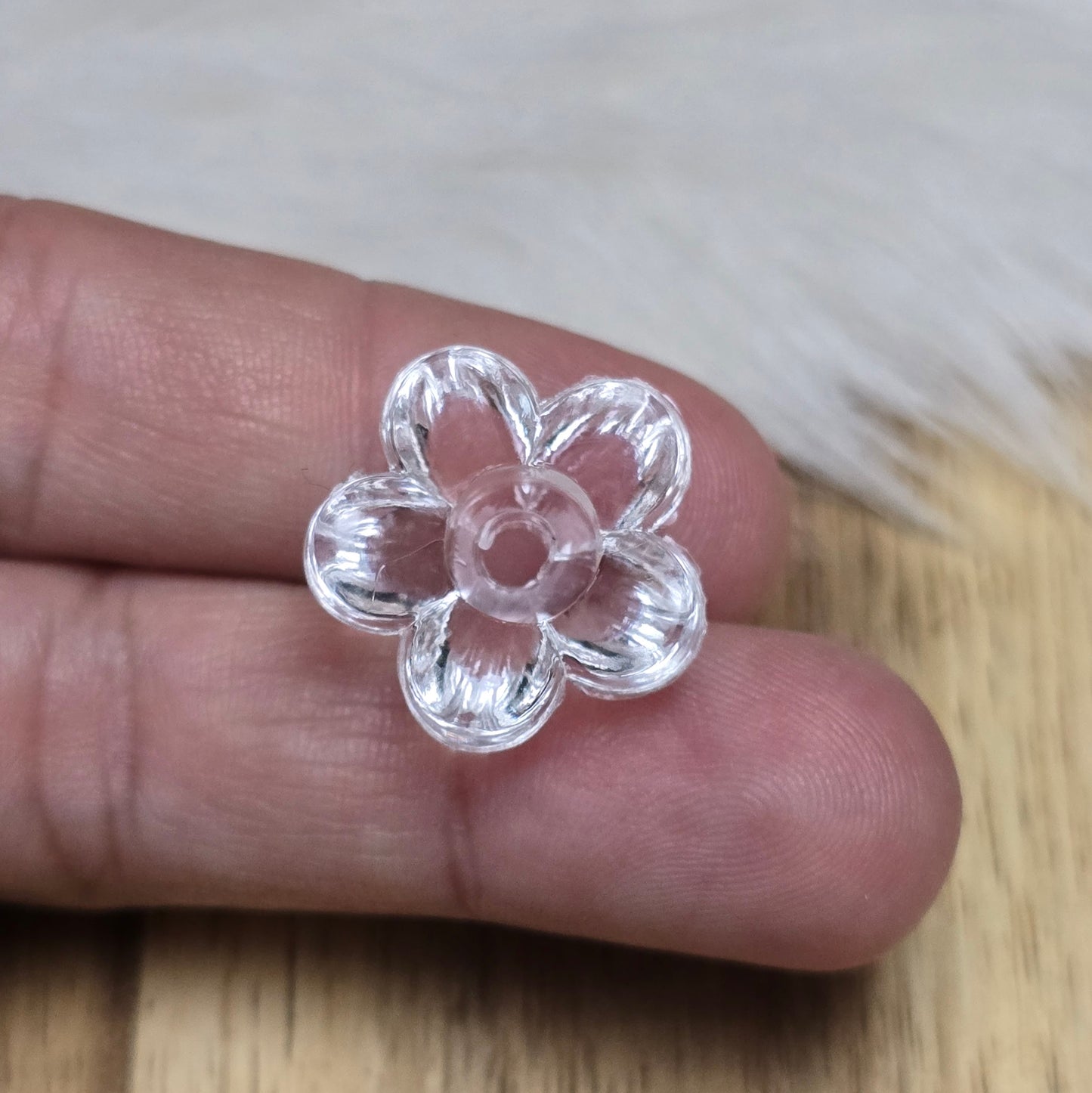 Klar transparente Acryl-Blumenperlen (18 mm) mit glänzender Oberfläche. Die filigrane Blütenform verleiht Schmuckstücken und Dekorationen eine elegante Note. Mit einem 3,5 mm großen Fädelloch lassen sie sich leicht auf Bänder oder Schnüre auffädeln. Ideal für DIY-Projekte, Hochzeiten oder Bastelarbeiten.