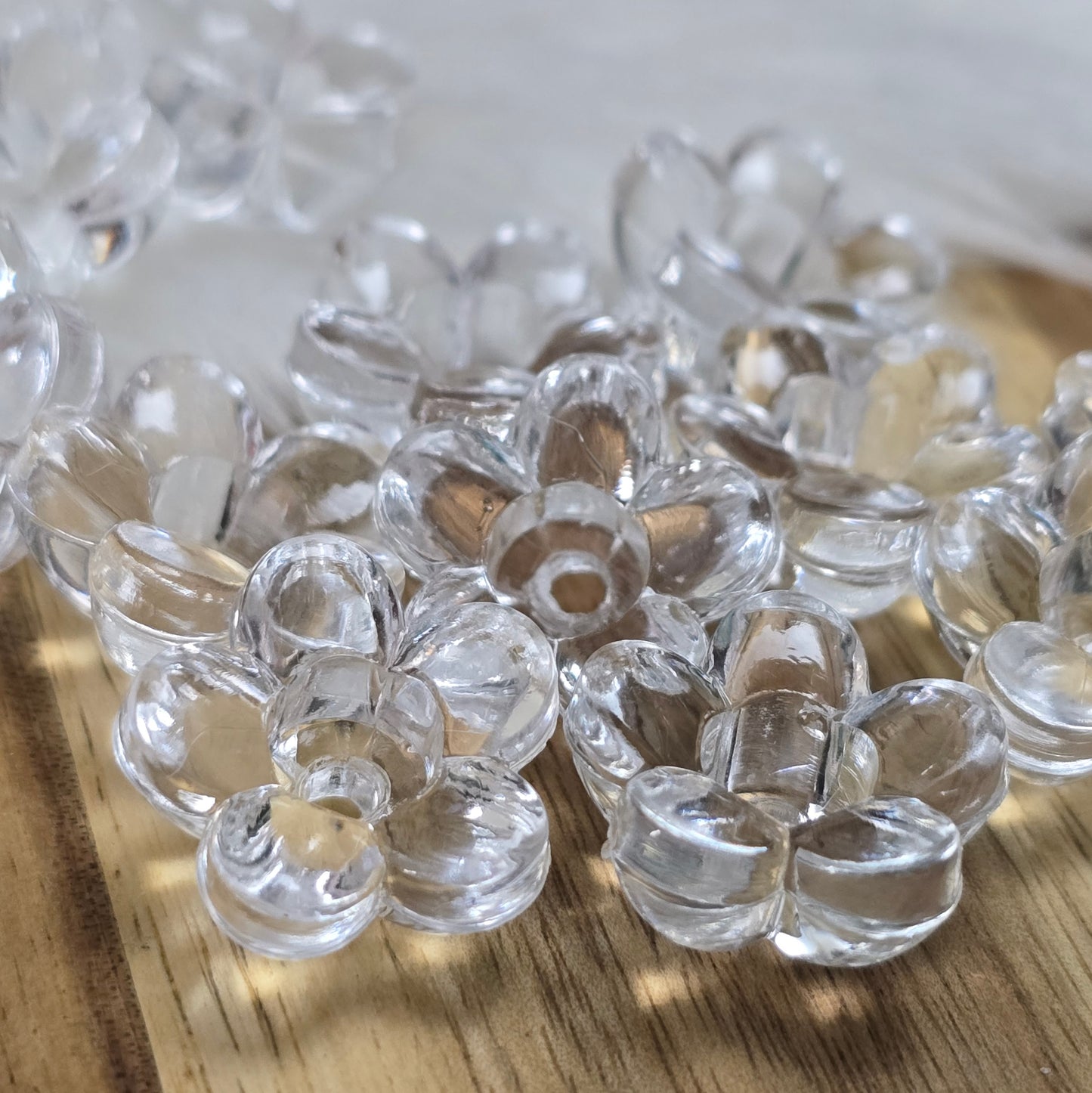 Klar transparente Acryl-Blumenperlen (18 mm) mit glänzender Oberfläche. Die filigrane Blütenform verleiht Schmuckstücken und Dekorationen eine elegante Note. Mit einem 3,5 mm großen Fädelloch lassen sie sich leicht auf Bänder oder Schnüre auffädeln. Ideal für DIY-Projekte, Hochzeiten oder Bastelarbeiten.