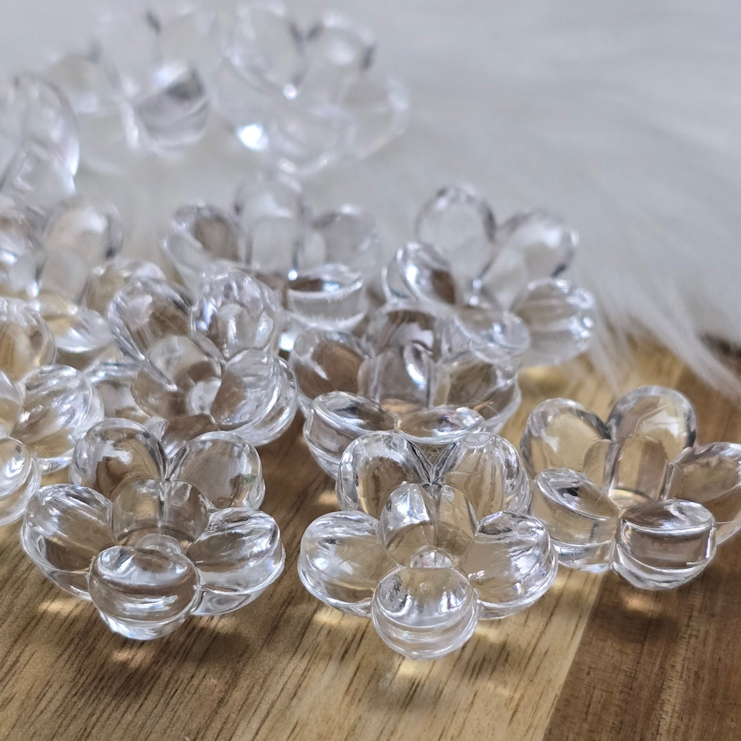 Klar transparente Acryl-Blumenperlen (18 mm) mit glänzender Oberfläche. Die filigrane Blütenform verleiht Schmuckstücken und Dekorationen eine elegante Note. Mit einem 3,5 mm großen Fädelloch lassen sie sich leicht auf Bänder oder Schnüre auffädeln. Ideal für DIY-Projekte, Hochzeiten oder Bastelarbeiten.