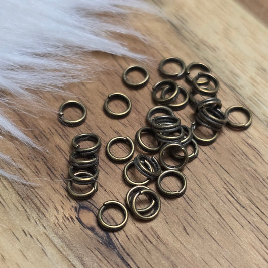 Das Bild zeigt 30 doppelte Binderinge in antikem Bronze-Finish mit 4mm im Durchmesser, ein unverzichtbares Zubehör für die Schmuckherstellung. Durch ihre doppelte Wicklung bieten sie eine besonders stabile und sichere Verbindung, sodass Anhänger, Charms und Verschlüsse zuverlässig befestigt bleiben.