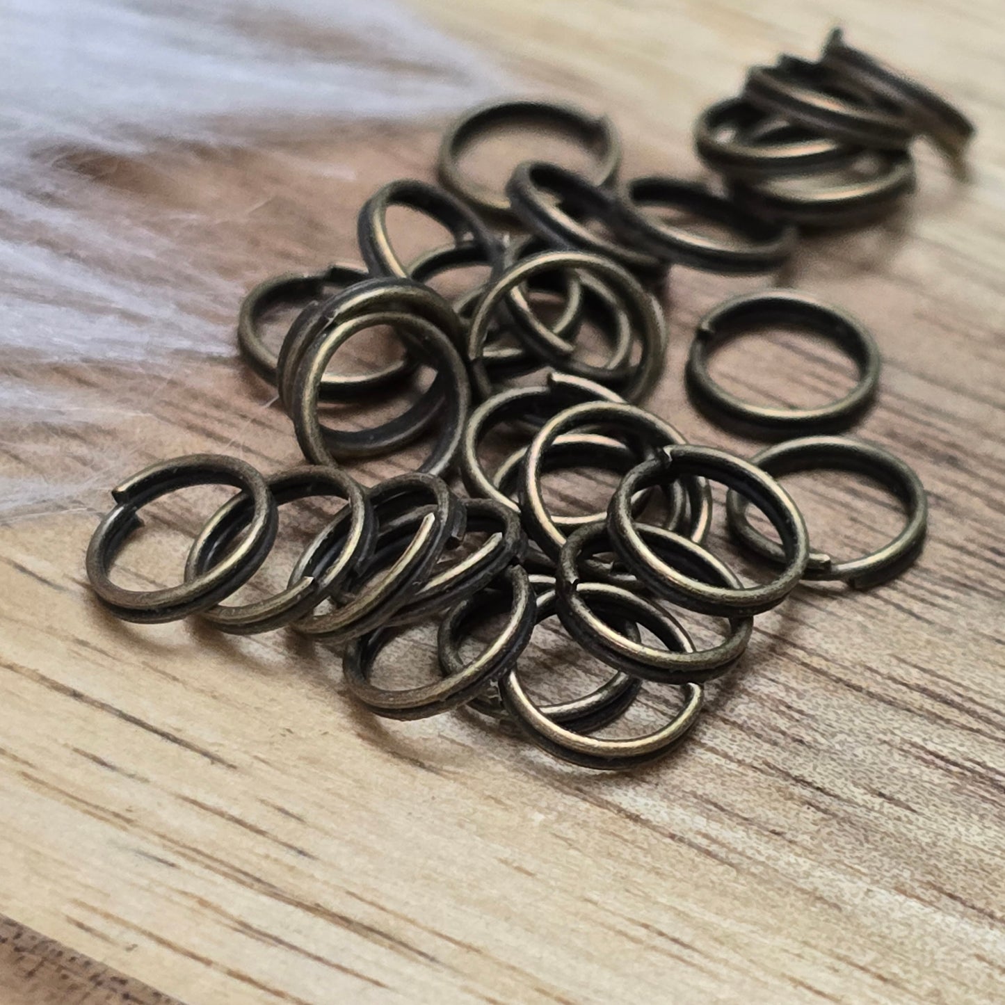 Das Bild zeigt 30 doppelte Binderinge in antikem Bronze-Finish mit 6mm Durchmesser. Die Verbindungsringe sind ein unverzichtbares Zubehör für die Schmuckherstellung. Durch ihre doppelte Wicklung bieten sie eine besonders stabile und sichere Verbindung, sodass Anhänger, Charms und Verschlüsse zuverlässig befestigt bleiben.
