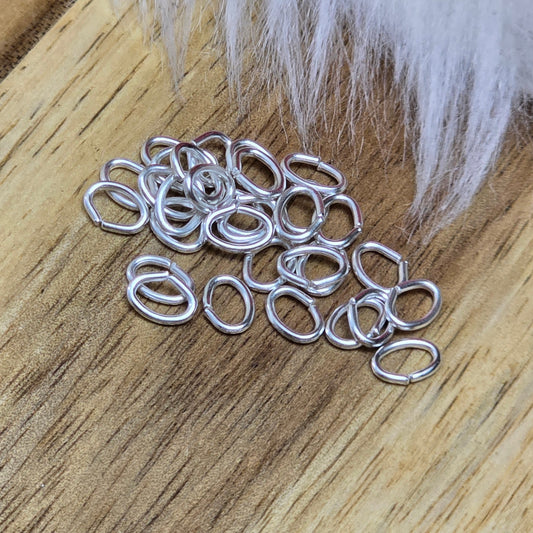 Das Bild zeigt 30 ovale, offenen Biegeringe in versilbert mit der Abmessung 5,4 x 4mm. Diese Verbindungsringe sind ein unverzichtbares Zubehör für die Schmuckherstellung. Ideal um Charms und Verschlüsse zuverlässig zu befestigen.