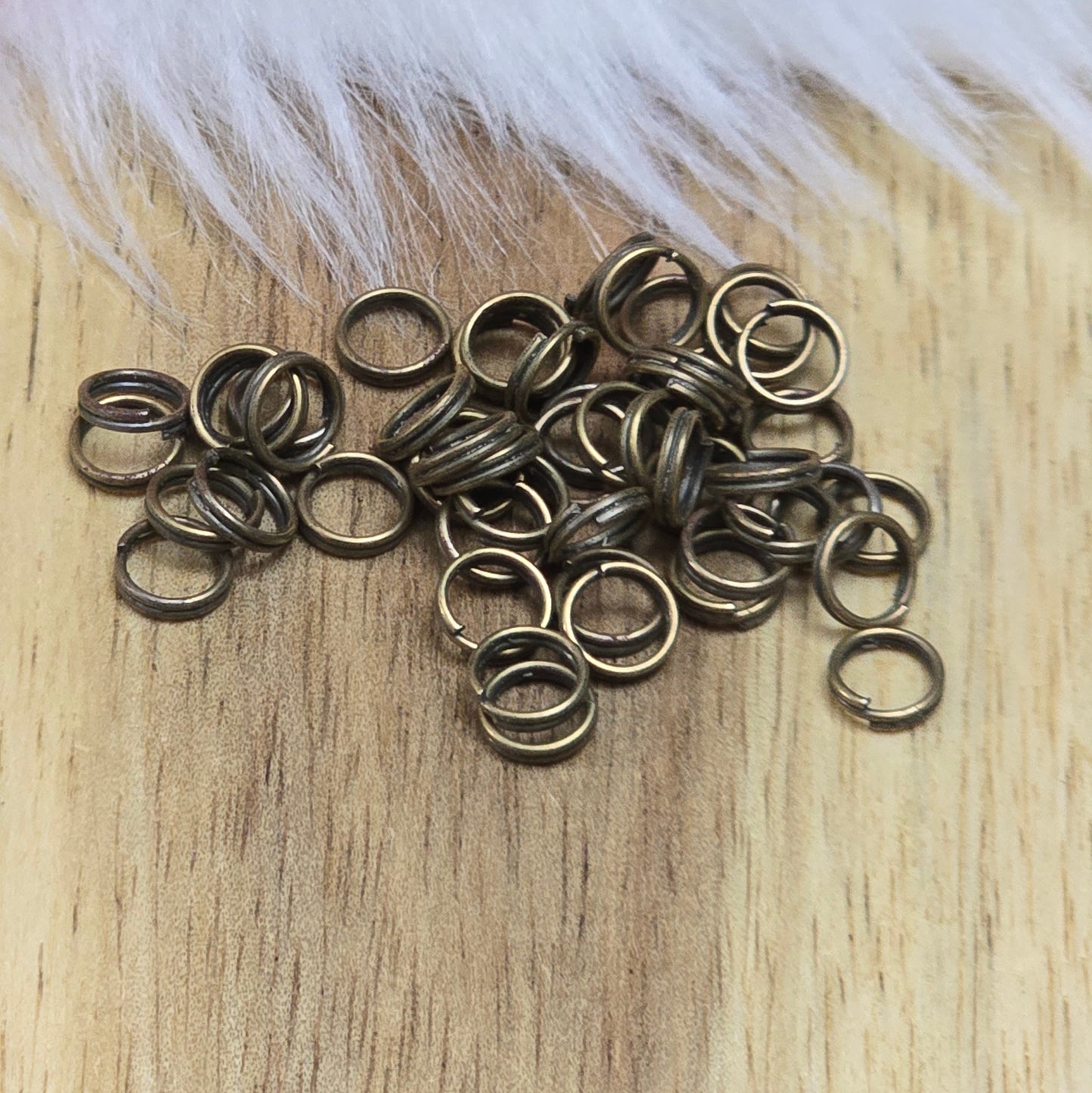Das Bild zeigt 50 doppelte Binderinge in antikem Bronze-Finish. Die Verbindungsringe sind ein unverzichtbares Zubehör für die Schmuckherstellung. Durch ihre doppelte Wicklung bieten sie eine besonders stabile und sichere Verbindung, sodass Anhänger, Charms und Verschlüsse zuverlässig befestigt bleiben.