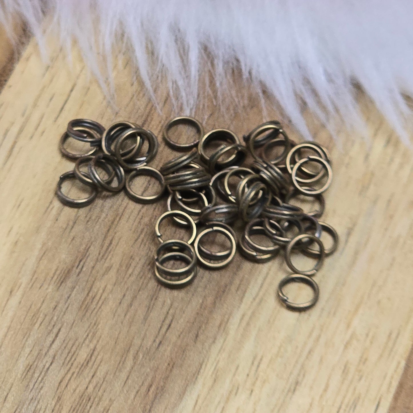 Das Bild zeigt 50 doppelte Binderinge in antikem Bronze-Finish. Die Verbindungsringe sind ein unverzichtbares Zubehör für die Schmuckherstellung. Durch ihre doppelte Wicklung bieten sie eine besonders stabile und sichere Verbindung, sodass Anhänger, Charms und Verschlüsse zuverlässig befestigt bleiben.