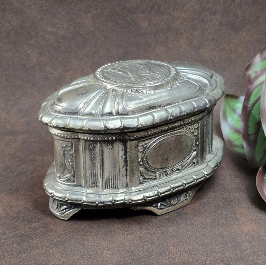 Antike Zinn-Schmuckschatulle mit barocker Kinderszene, 1920er Jahre. Ein dekoratives Sammlerstück mit Vintage-Patina – ideal für nostalgische Interieurs.