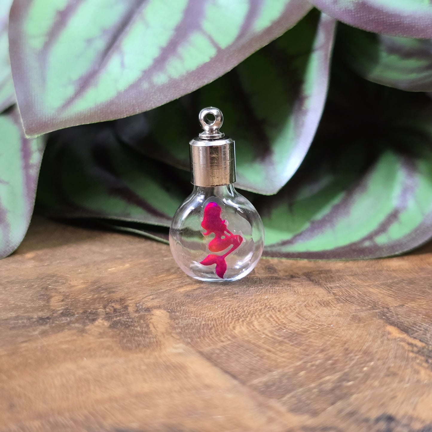 Kleine Glasflasche mit Schraubverschluss und pinkem Meerjungfrau-Motiv, ideal als Kettenanhänger und tragbare Parfümflasche.