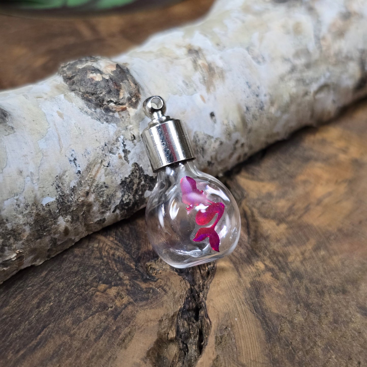 Kleine Glasflasche mit Schraubverschluss und pinkem Meerjungfrau-Motiv, ideal als Kettenanhänger und tragbare Parfümflasche.