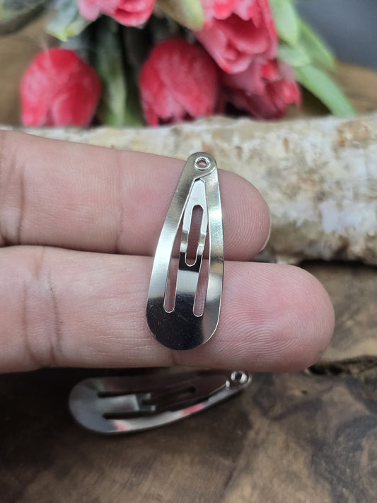 Ein einzelner silberner Klick-Haarspangen-Rohling auf zwei Fingern präsentiert zur Veranschaulichung der Größe von 30 mm.