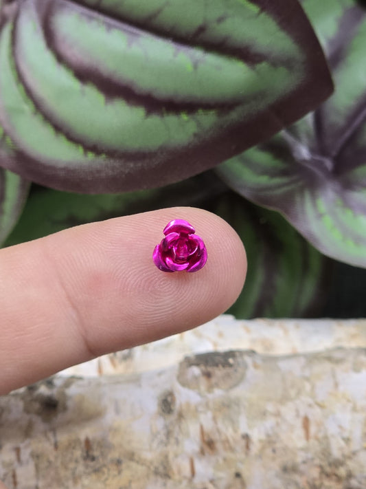 Kleine rosa Aluminium-Rosenperle 7 mm als Größenvergleich auf der Fingerspitze