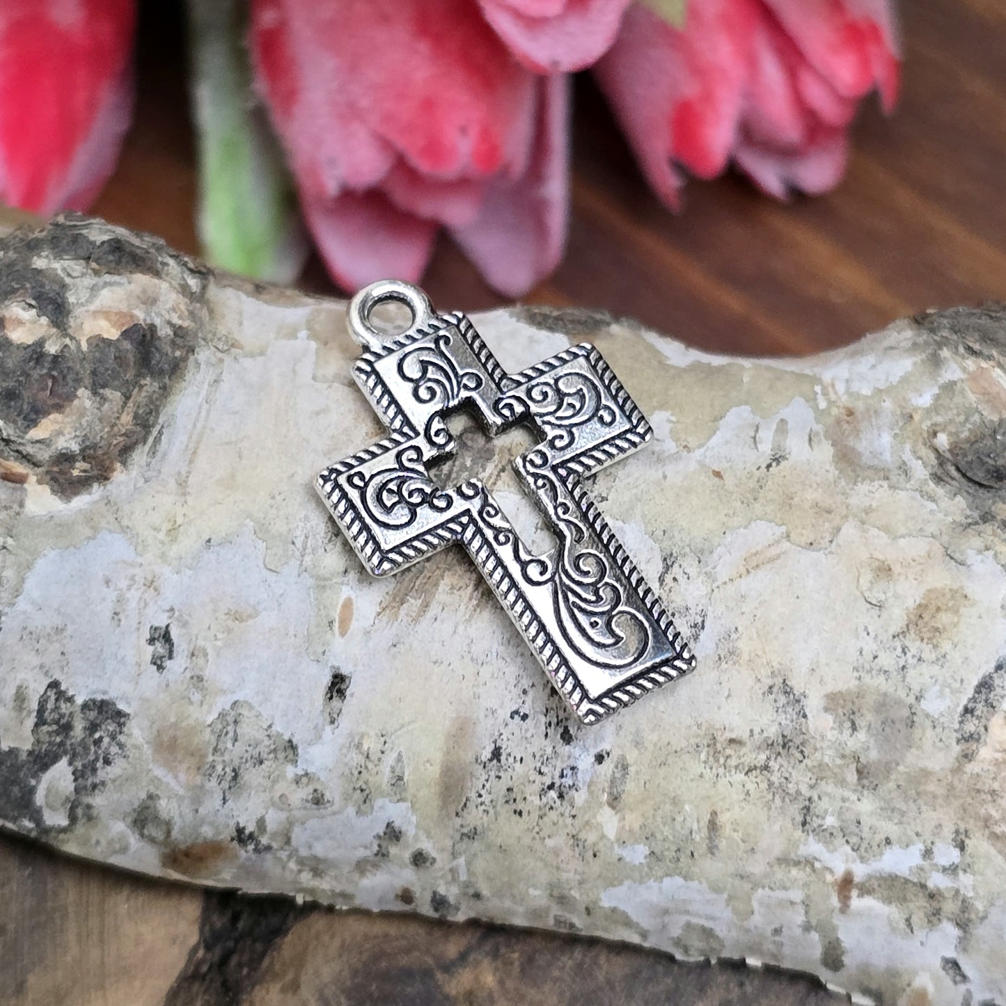 Das Bild zeigt einen charmanten Kreuz-Anhänger in antik silberfarbiger Ausführung. Mit einer Größe von 23 mm sind sie ideal für Ihre individuelle Schmuckherstellung.