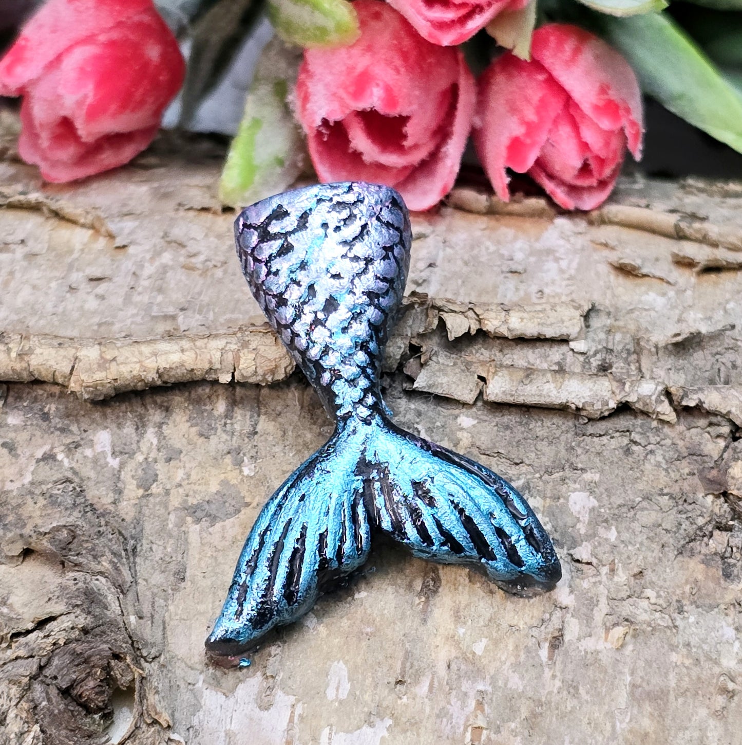 Das Bild zeigt eine handgefertigte Schwanzflosse einer Meerjungfrau aus Kunstharz. Die Flosse ist detailliert bemalt in sanften Farben und hat eine flache Rückseite. Sie eignet sich ideal als Cabochon für Schmuck oder als Dekoration für Bastelprojekte.