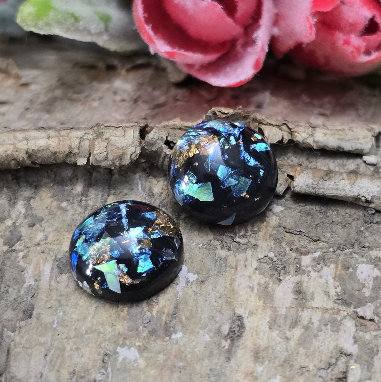 Das Bild zeigt runde Cabochons mit einem Durchmesser von 12 mm. Sie sind tiefschwarz und haben eine glatte, glänzende Oberfläche. Im Inneren der Cabochons befinden sich feine, schimmernde Flakes, die je nach Lichteinfall dezent funkeln. Die Flakes erzeugen kleine, reflektierende Lichtpunkte, die dem Schwarz eine besondere Tiefe verleihen. Die Cabochons wirken edel und modern. Sie eignen sich für die Schmuckherstellung, beispielsweise für Ringe, Anhänger oder Ohrstecker.