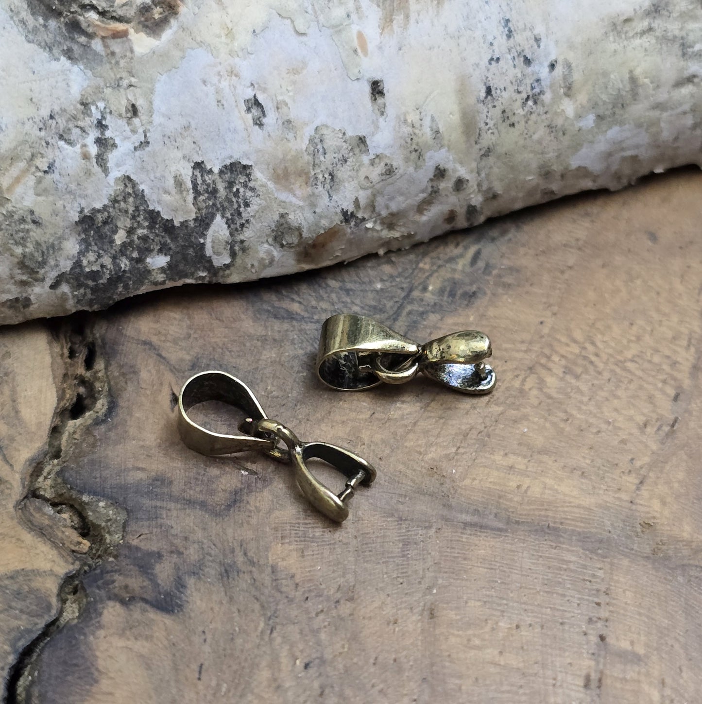 Das Bild zeigt 2 Collierschlaufen mit Dorn antik bronzefarbig - 5 x 4mm
Diese Collierschlaufen sind ideal, um flache Schmucksteine mit oberer Bohrung in Anhänger zu verwandeln.
