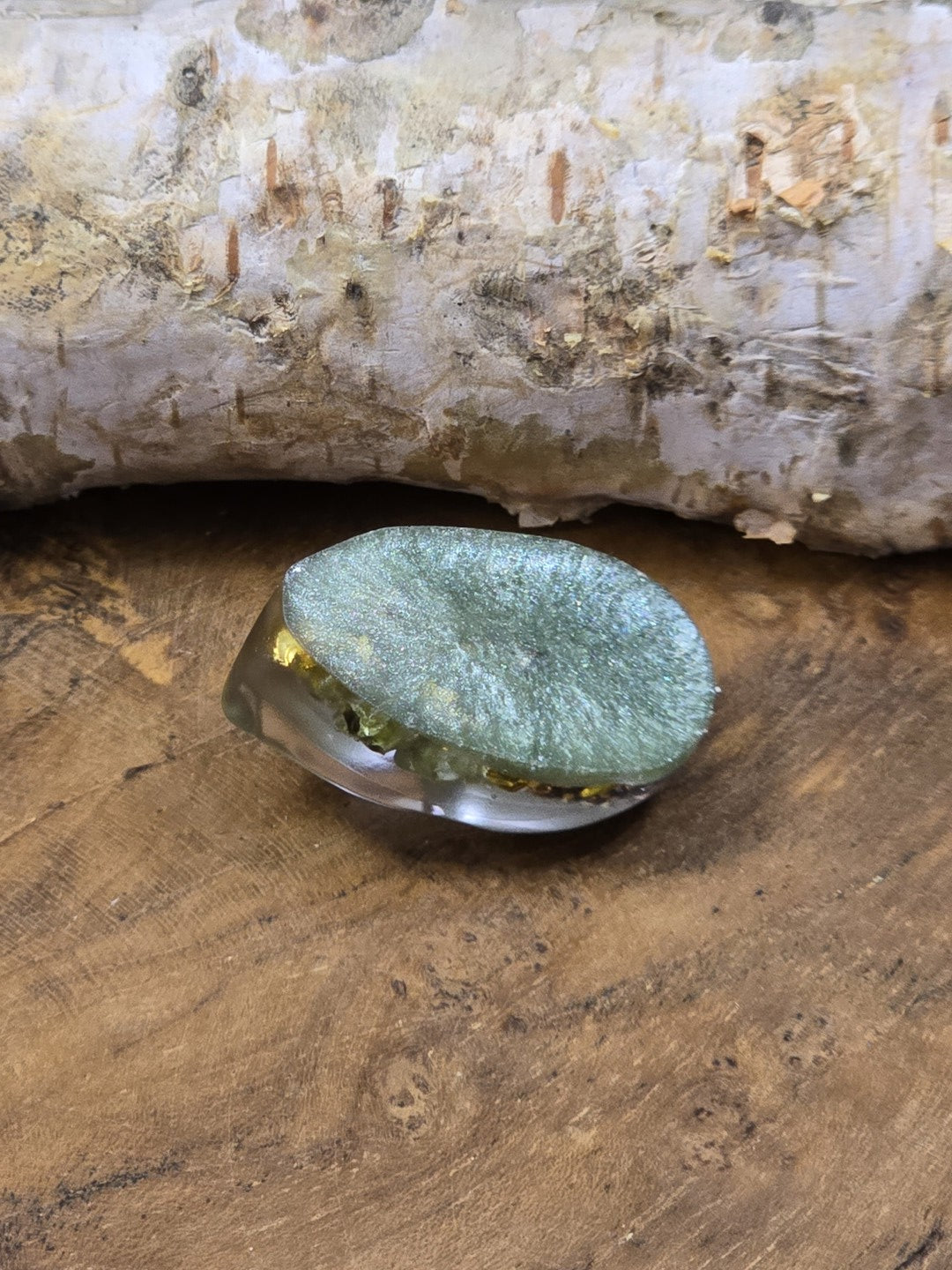 Rückseite eines schimmernden grünen Resin-Cabochons mit Cabochonform für DIY-Schmuckprojekte