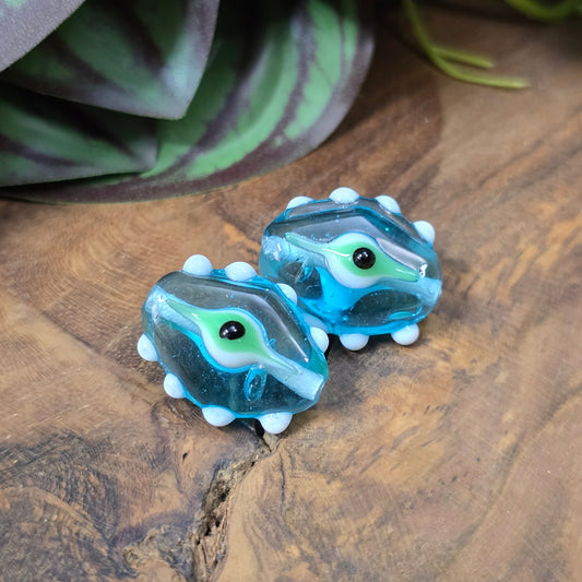 2 handgefertigte Lampwork-Glasperlen in Blau, Oval mit Noppen & Augenmotiv. Einzigartiges Material für kreative Schmuckherstellung.