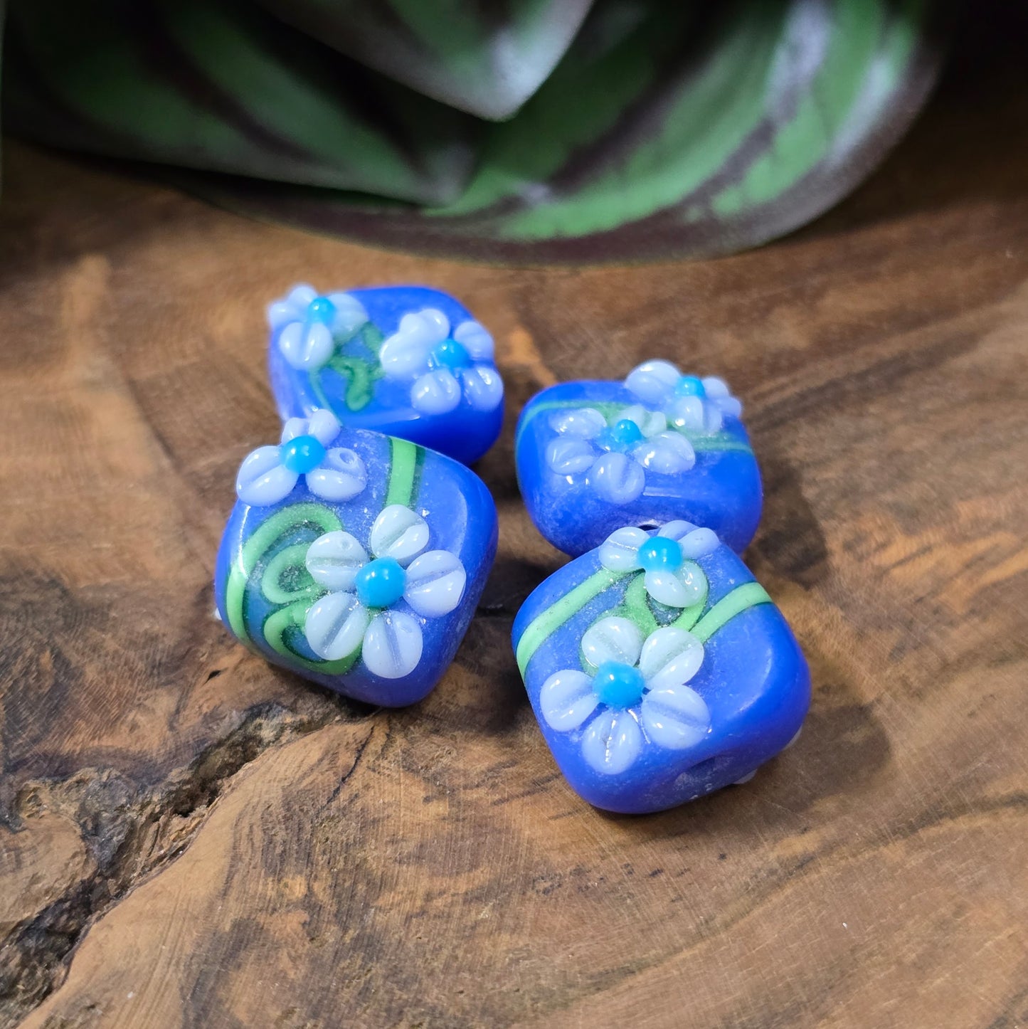 4 handgefertigte Lampwork-Glasperlen, quadratisch in Blau mit Blütendekor. Hochwertiges Material für individuelle Schmuckherstellung.