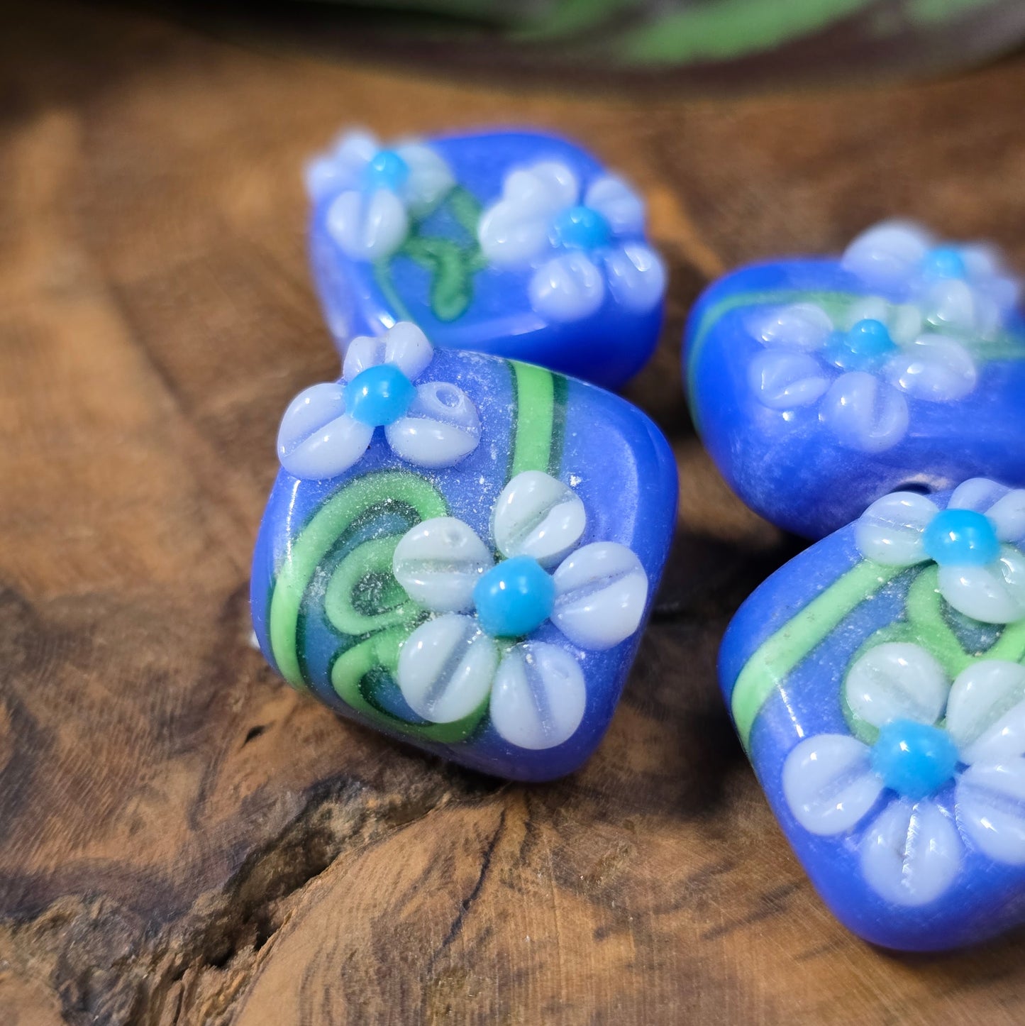 4 handgefertigte Lampwork-Glasperlen, quadratisch in Blau mit Blütendekor. Hochwertiges Material für individuelle Schmuckherstellung.