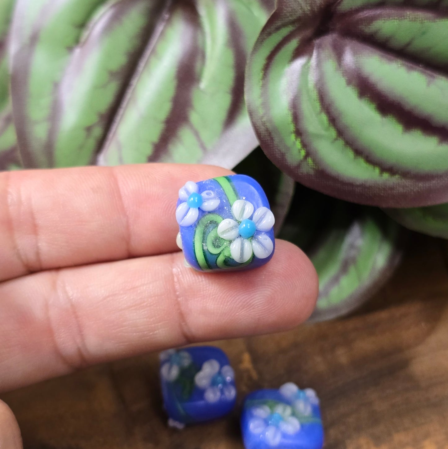 4 handgefertigte Lampwork-Glasperlen, quadratisch in Blau mit Blütendekor. Hochwertiges Material für individuelle Schmuckherstellung.