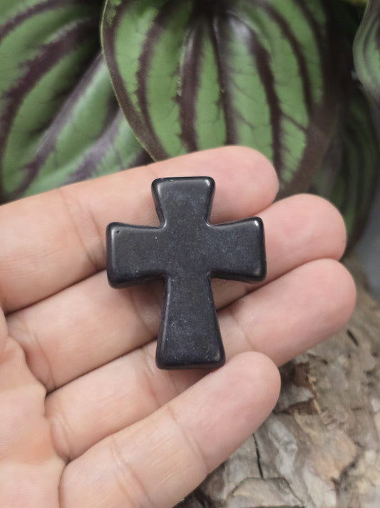 Schwarze Howlith Kreuzperle (36 mm) auf einer Hand präsentiert als Größenvergleich für DIY-Schmuck