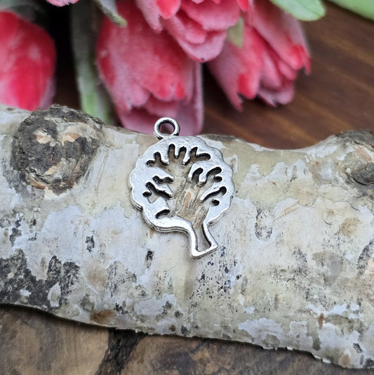 Das Bild zeigt einen Anhänger in Form eines Baums in antik silberfarbig mit der Silhouette eines Baum in der Mitte. Ideale Schmuckkomponenten für Ohrringe und Armbänder.