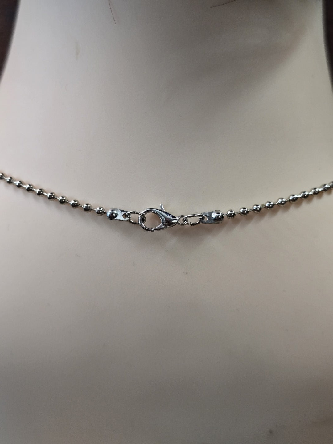 Nahaufnahme des stabilen Karabinerverschlusses der dunkelsilbernen Metallkugelkette.