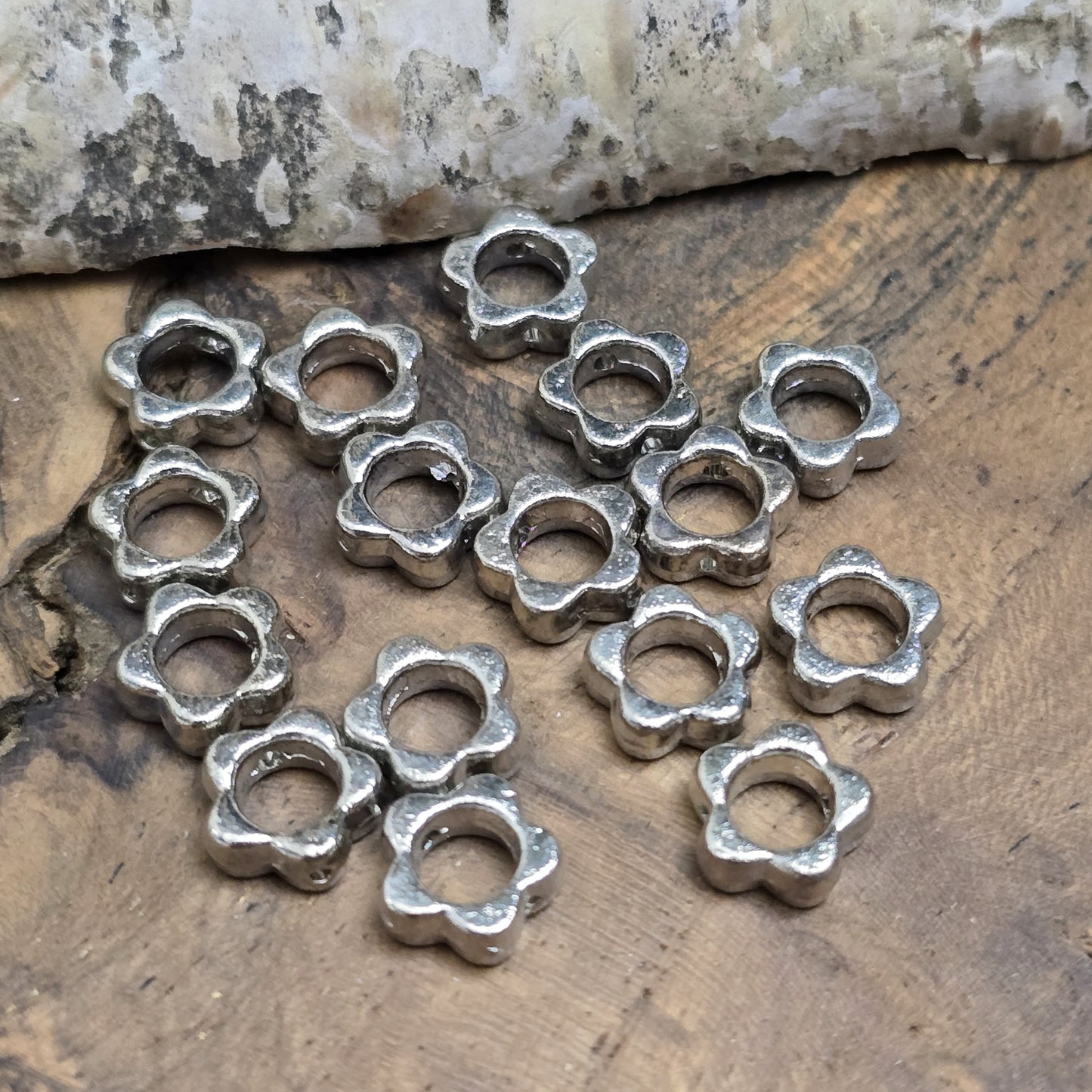 16 Metallperlen in Blumenform, Antiksilber, 8 mm. Jede Perle besticht durch ein filigranes Blumenmuster. Das längs verlaufende Fädelloch ermöglicht einfaches Aufreihen. Perfekt für Armbänder, Ketten oder andere kreative Schmuckideen. Set: 16 Stück.