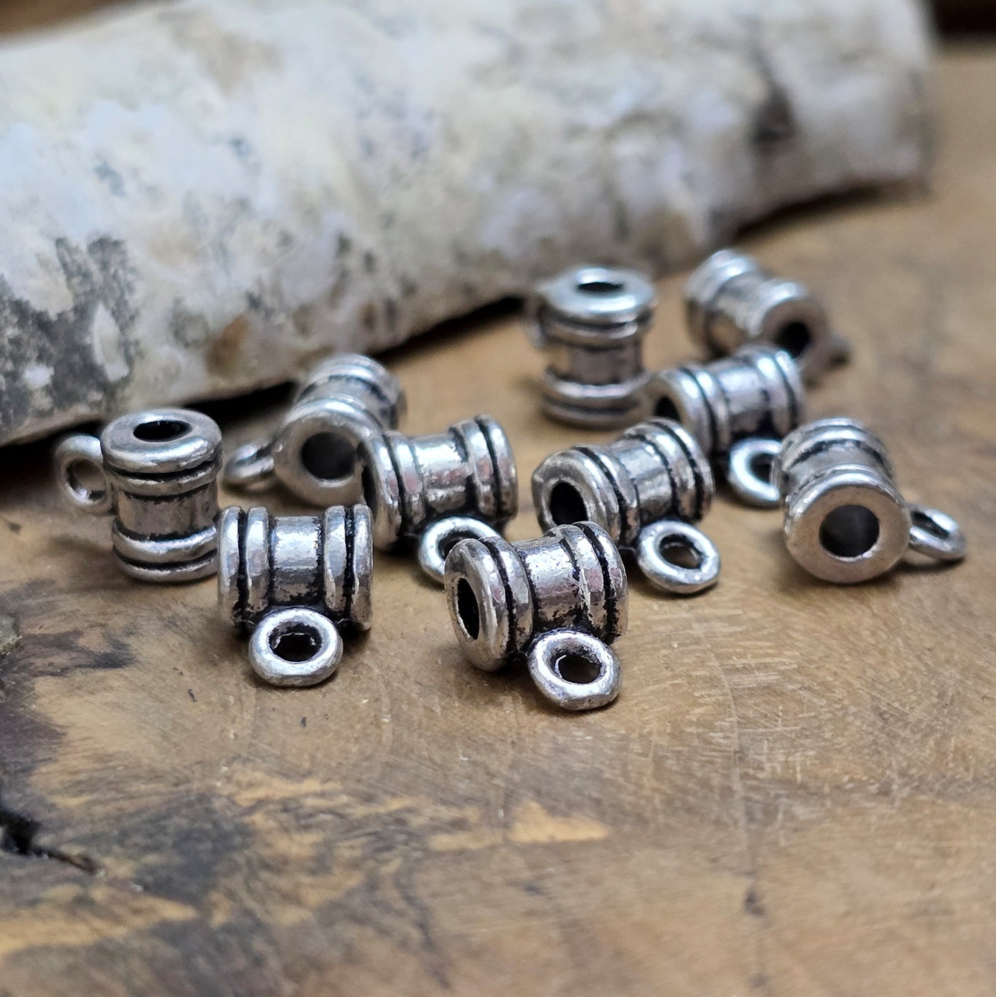 Das Bild zeigt antiksilberfarbene Metallperlen mit Öse. Sie sind eine ideale Ergänzung für kreative Schmuckprojekte. Dank des großzügigen 2,5-mm-Lochs lassen sie sich mühelos auf verschiedene Bänder und Kordeln auffädeln. Die zusätzliche Öse eröffnet zahlreiche Designmöglichkeiten, um Schmuckstücke individuell zu gestalten.